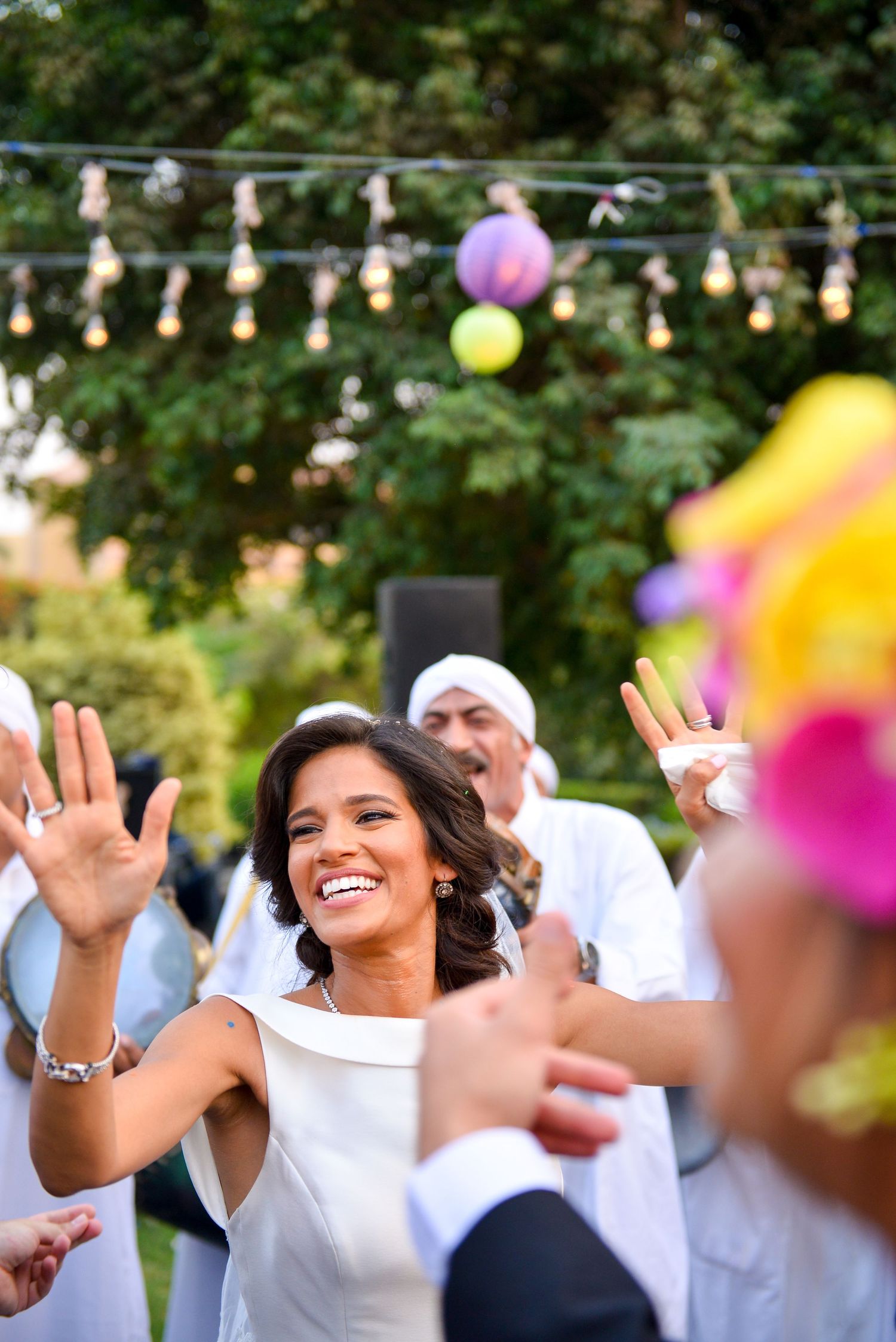 Celebratory dancing at an outdoor party with string lights and colorful decorations.