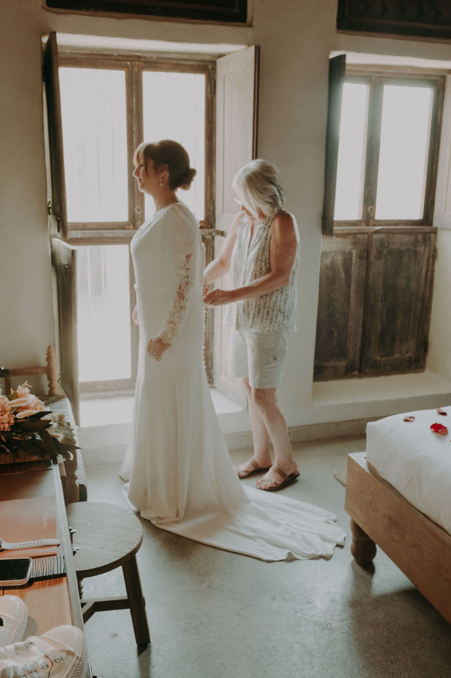 A wedding dress preparation scene in a bright, minimalist room with natural window light.