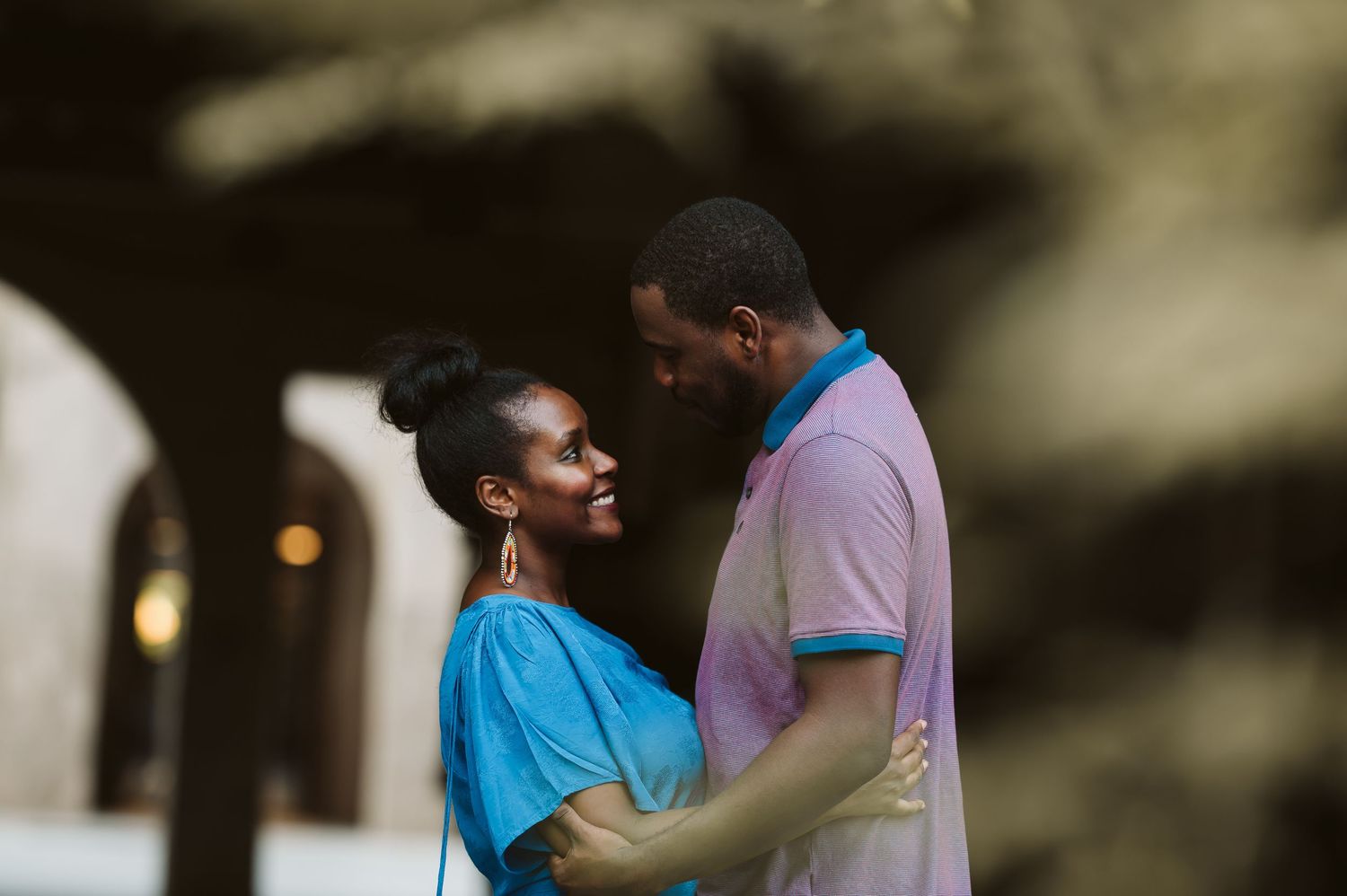 A couple shares a tender moment while sitting on outdoor steps wearing blue and purple outfits.