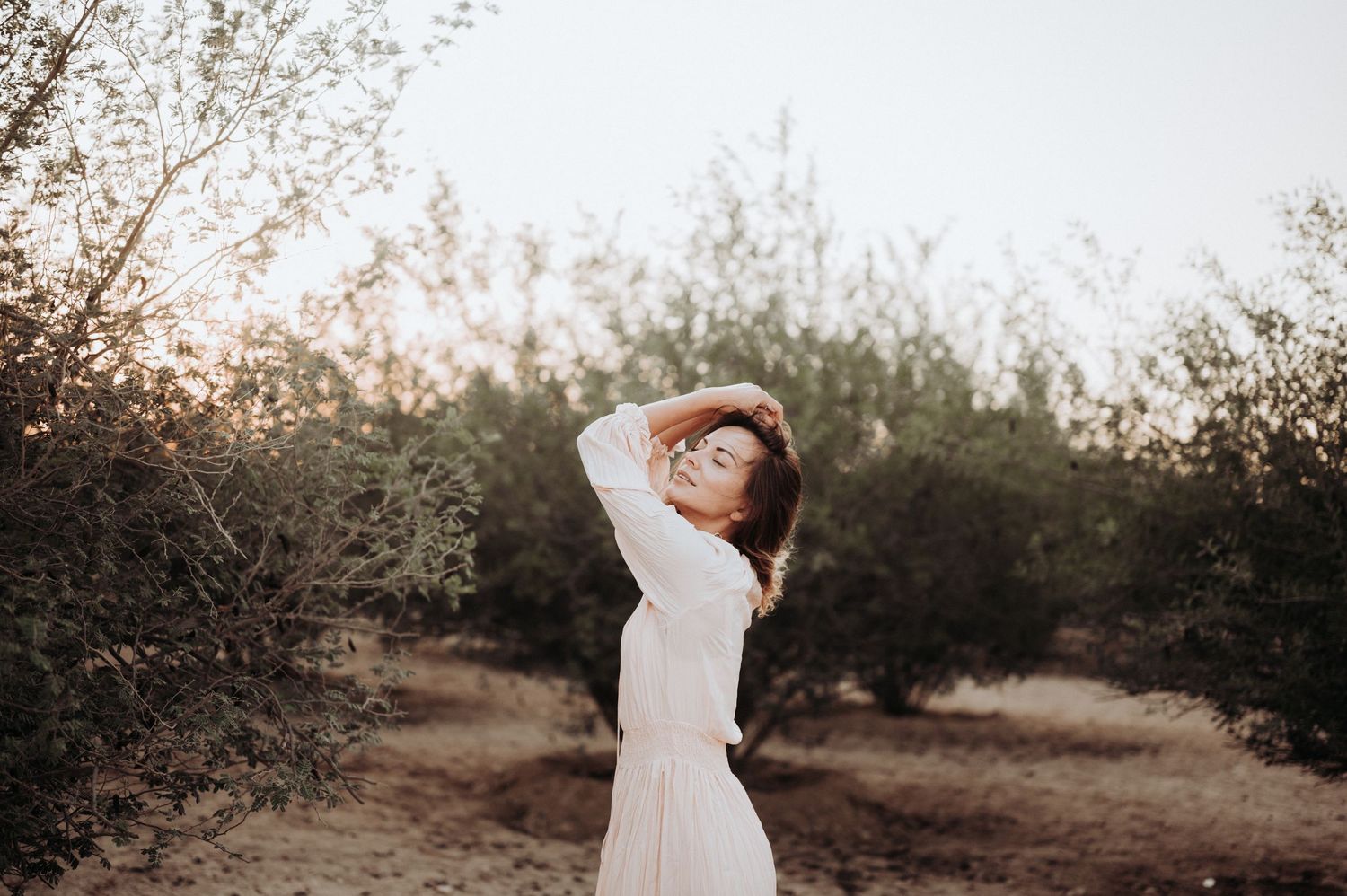 A dreamy outdoor photoshoot at sunset with soft natural lighting and desert brush.