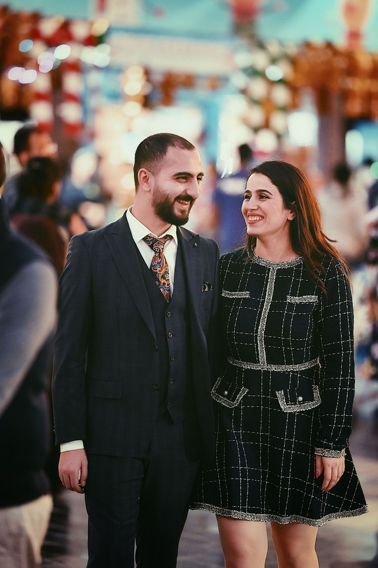 Couple in matching dark outfits share joyful moment at carnival.