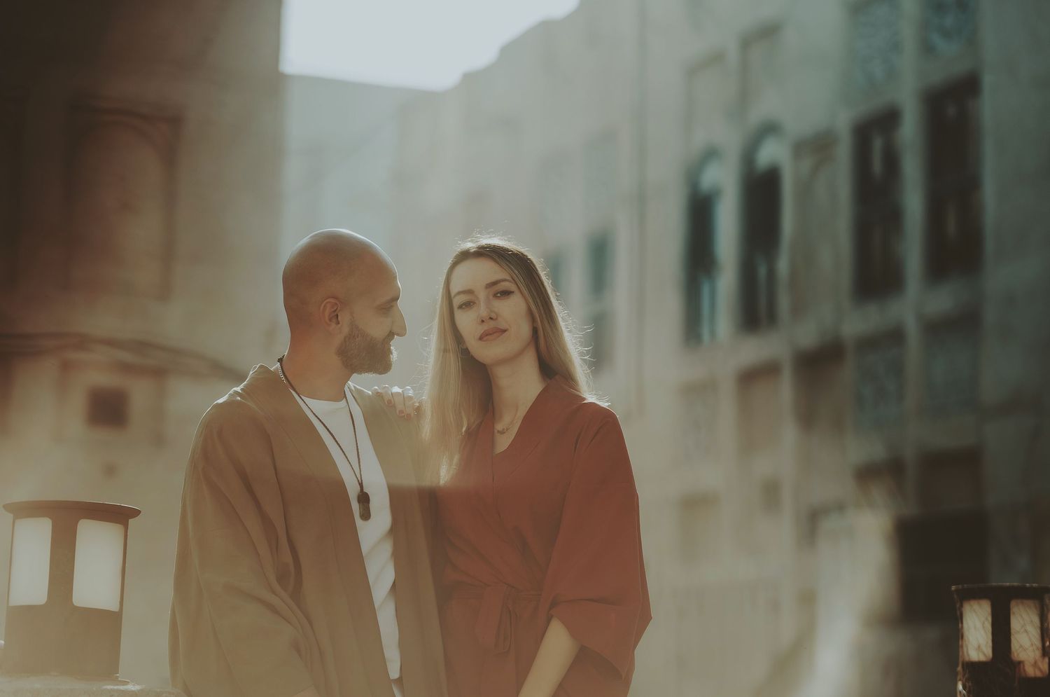 Couple photographed through soft focus lens against urban Middle Eastern architecture.