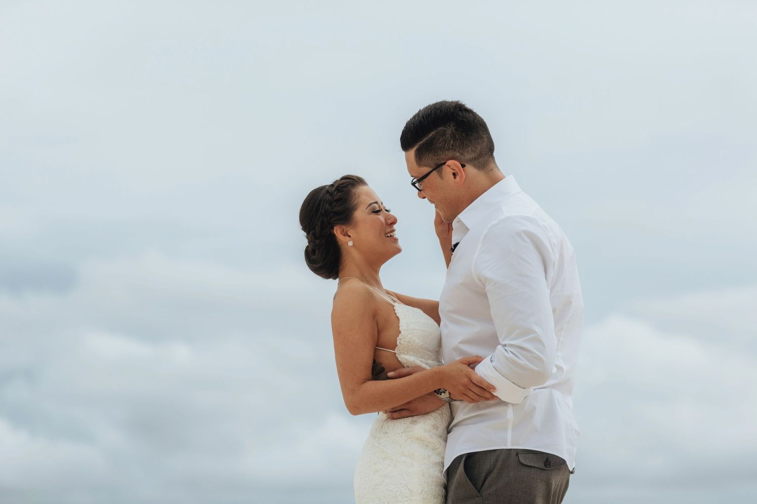 Couple shares tender moments during a beach photoshoot with cloudy backdrop.
