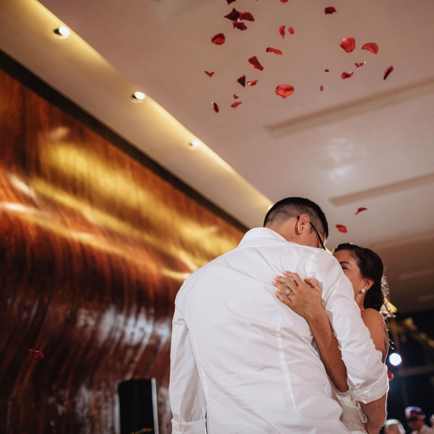 A romantic dance moment under warm lighting with red rose petals falling from above.