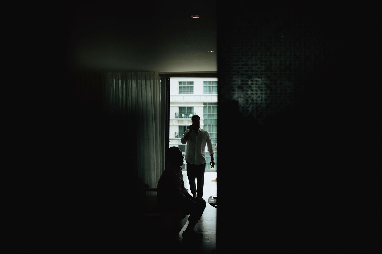 Silhouettes of people moving in a dark room with window light.