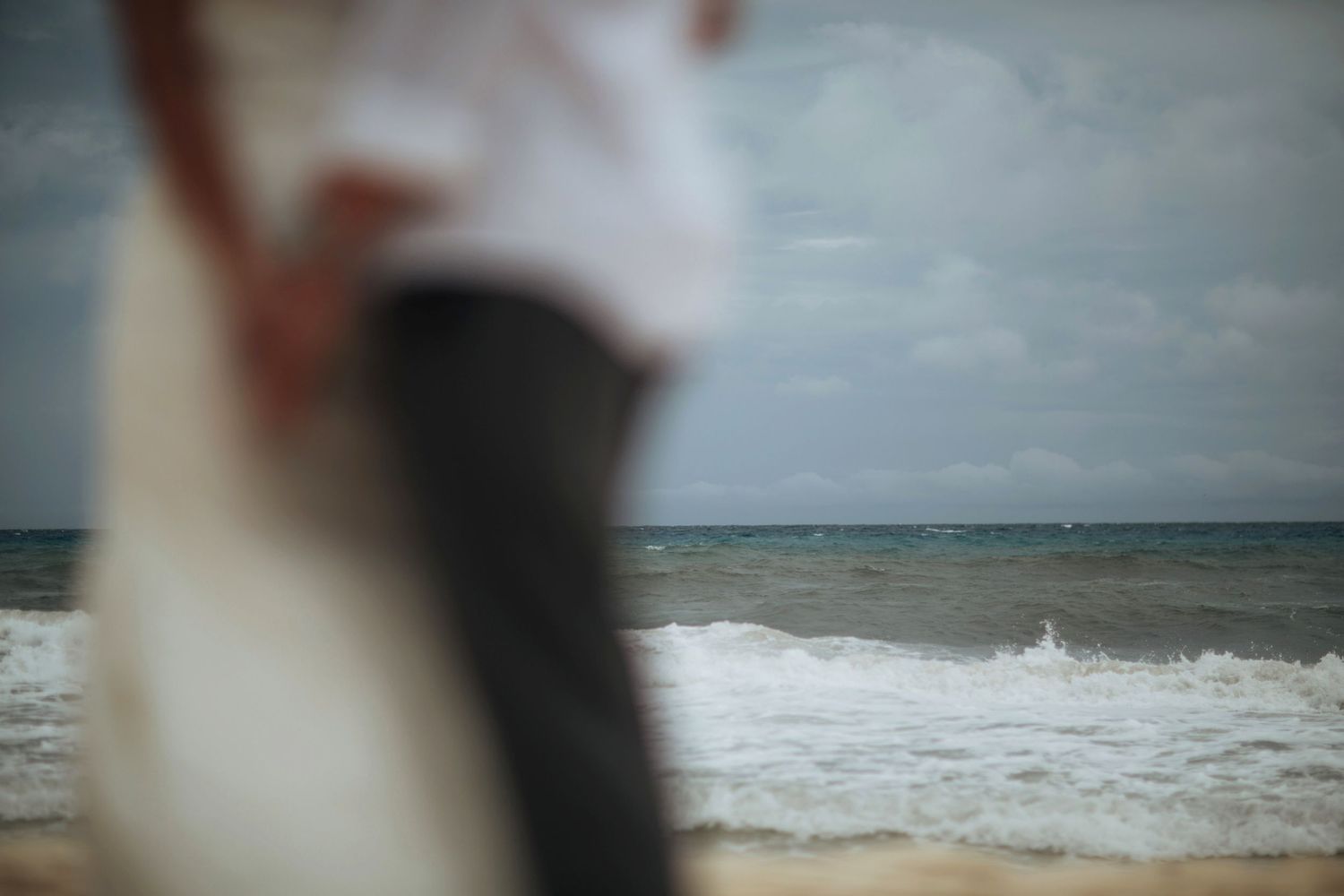 Blurred beach scene with waves and cloudy horizon.