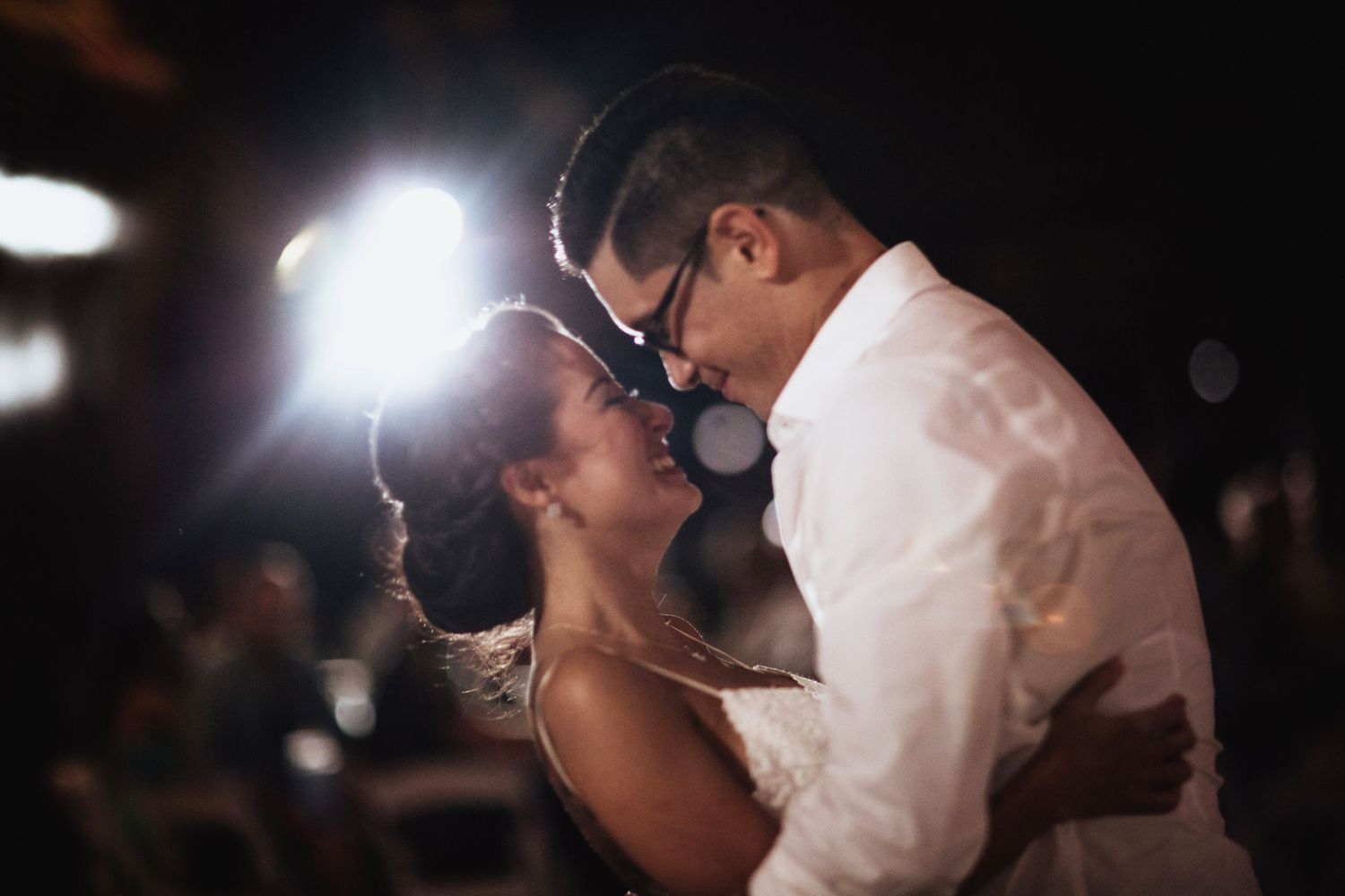 A couple dances together under dramatic lighting at an evening event.