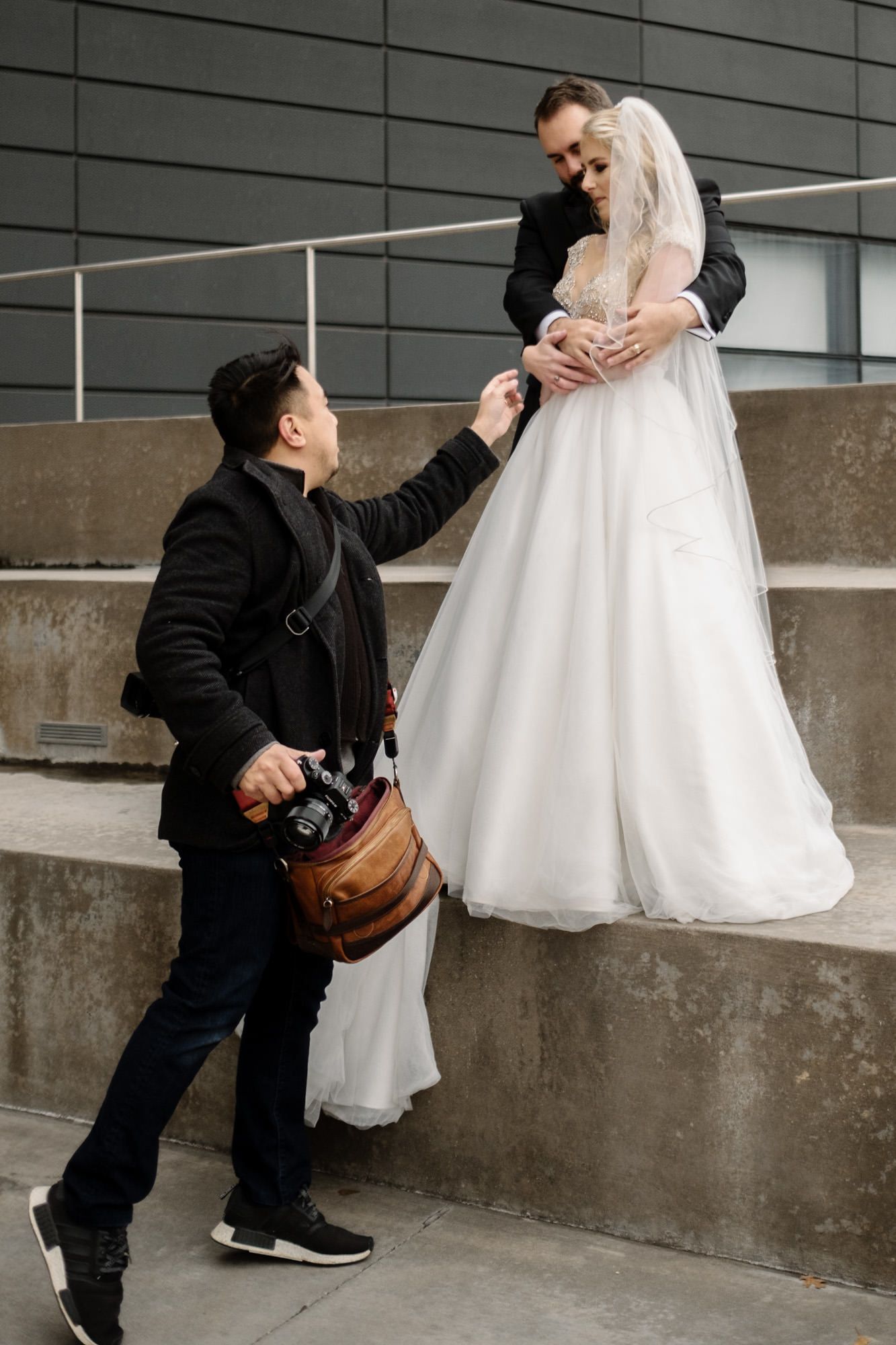Wedding photographer in black capturing shots in urban concrete setting. Jojo Pangilinan Photographers, Dallas based Destination wedding