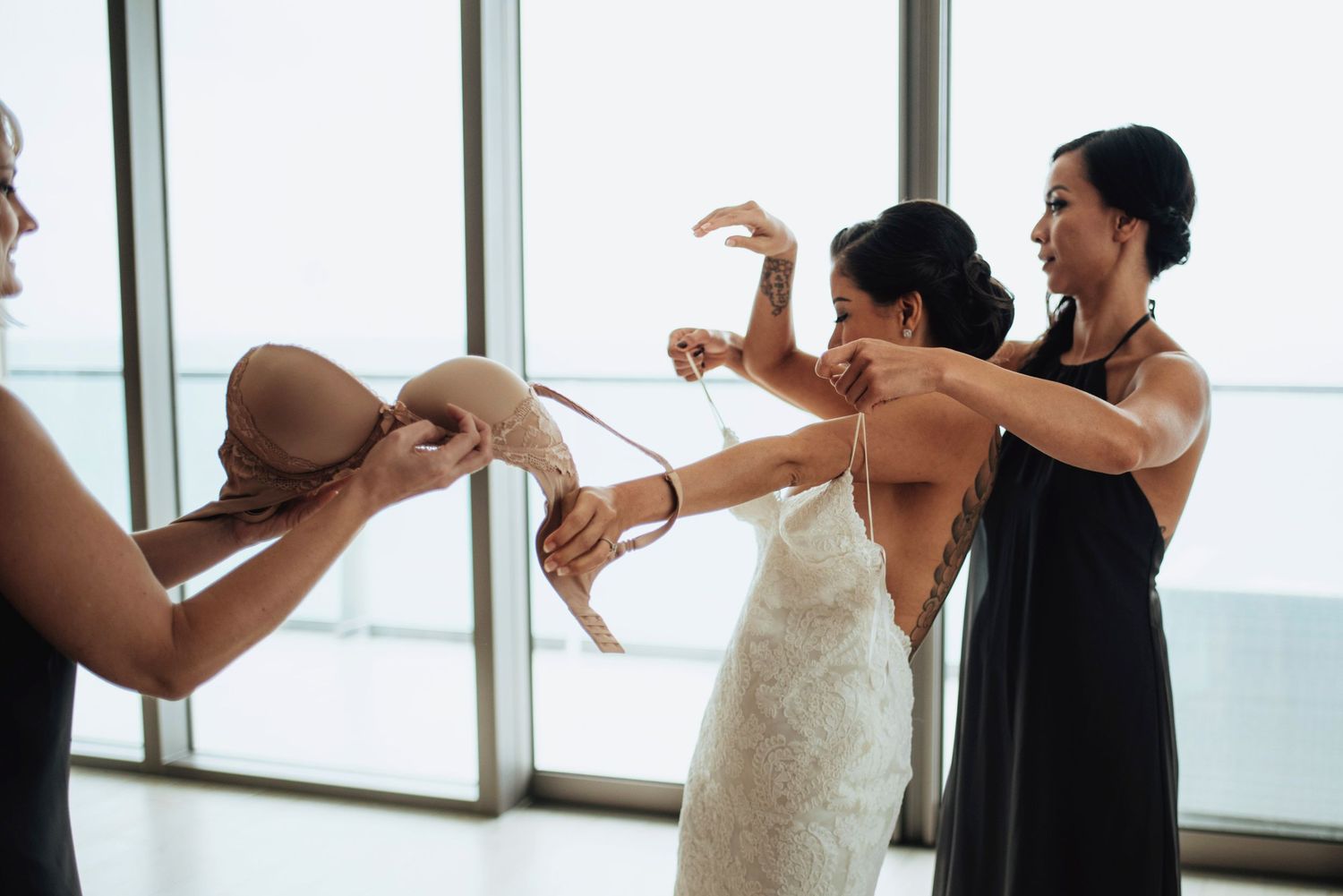 Two people in formal attire dancing together in front of large windows.
