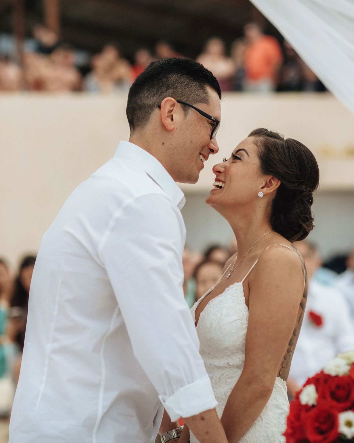 Intimate wedding ceremony moment on a beachfront with white decor.