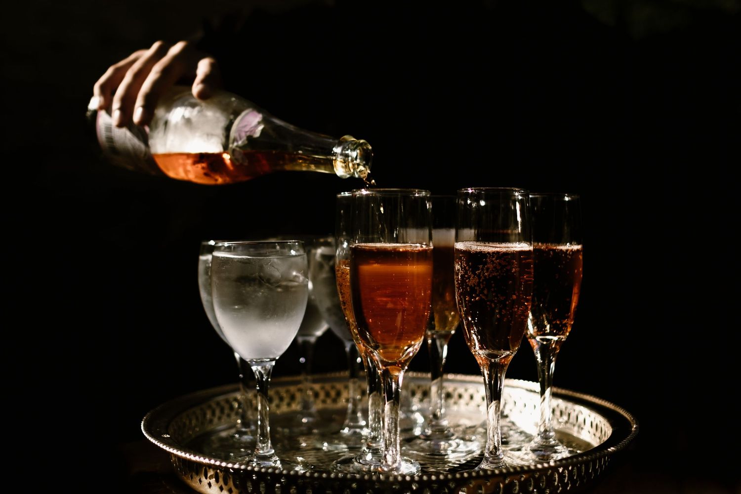 Collection of wedding reception drinks and glasses on dark background.