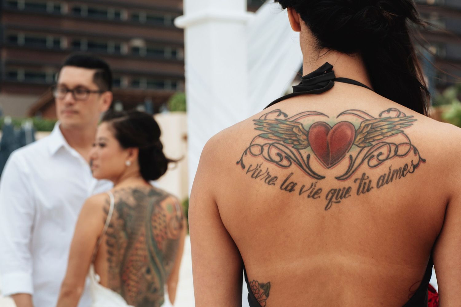 Close-up of decorative back tattoos at a beach wedding.