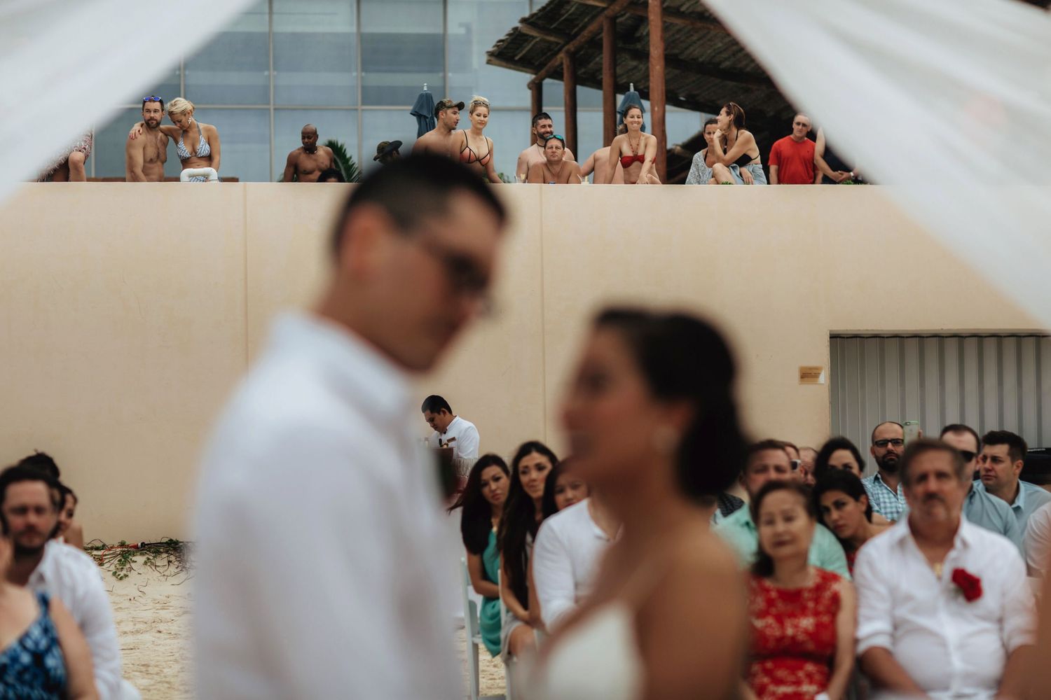 Beachside wedding celebration with guests watching the ceremony.