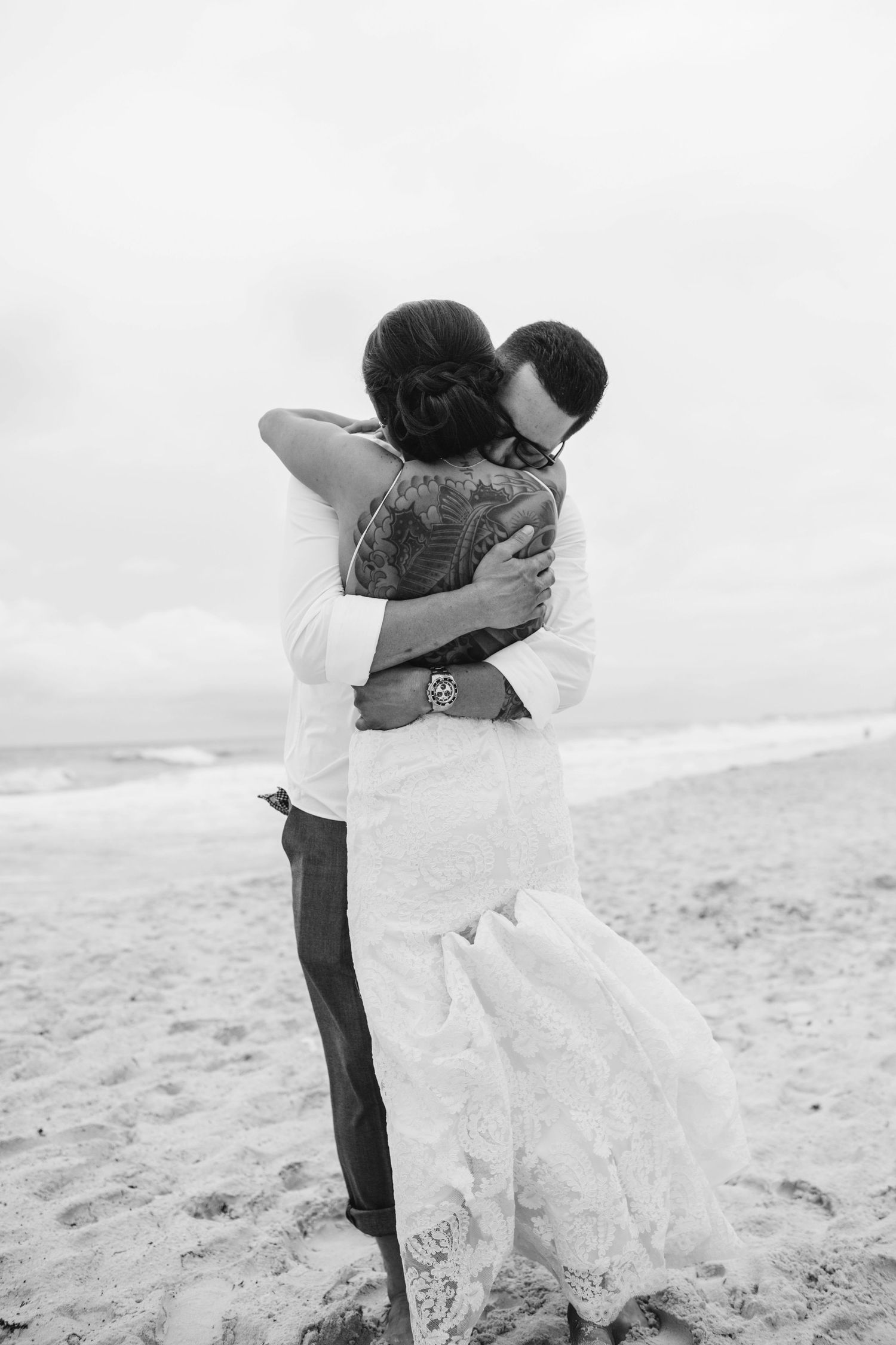 Black and white beach photography capturing intimate moments in the sand.