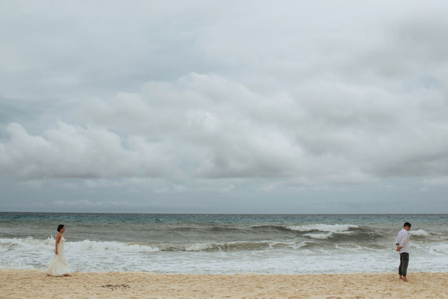 A romantic beach photoshoot with cloudy skies and ocean waves in the distance.