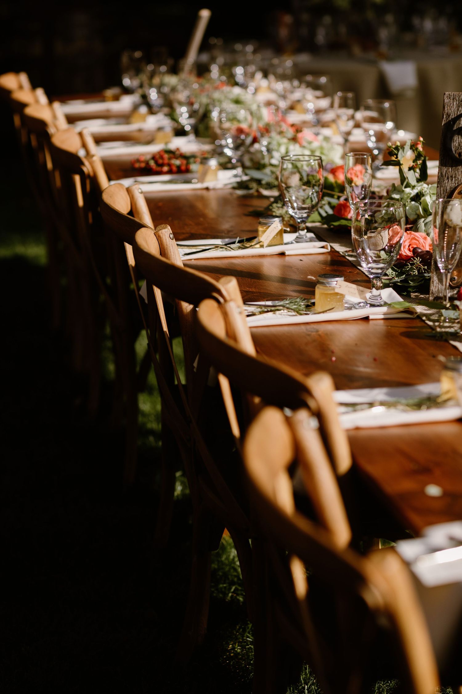 Elegant wooden reception tables set with greenery and place settings in natural light.