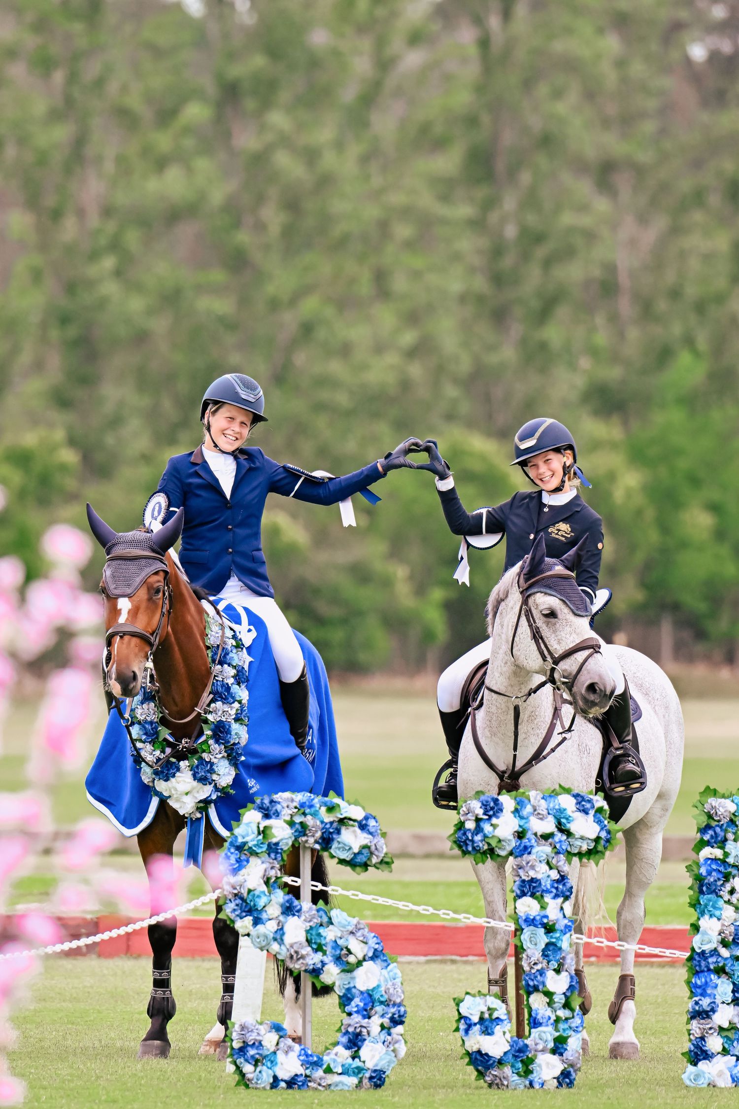 Horse and rider jumping over decorative blue and white floral obstacles during an equestrian competition.