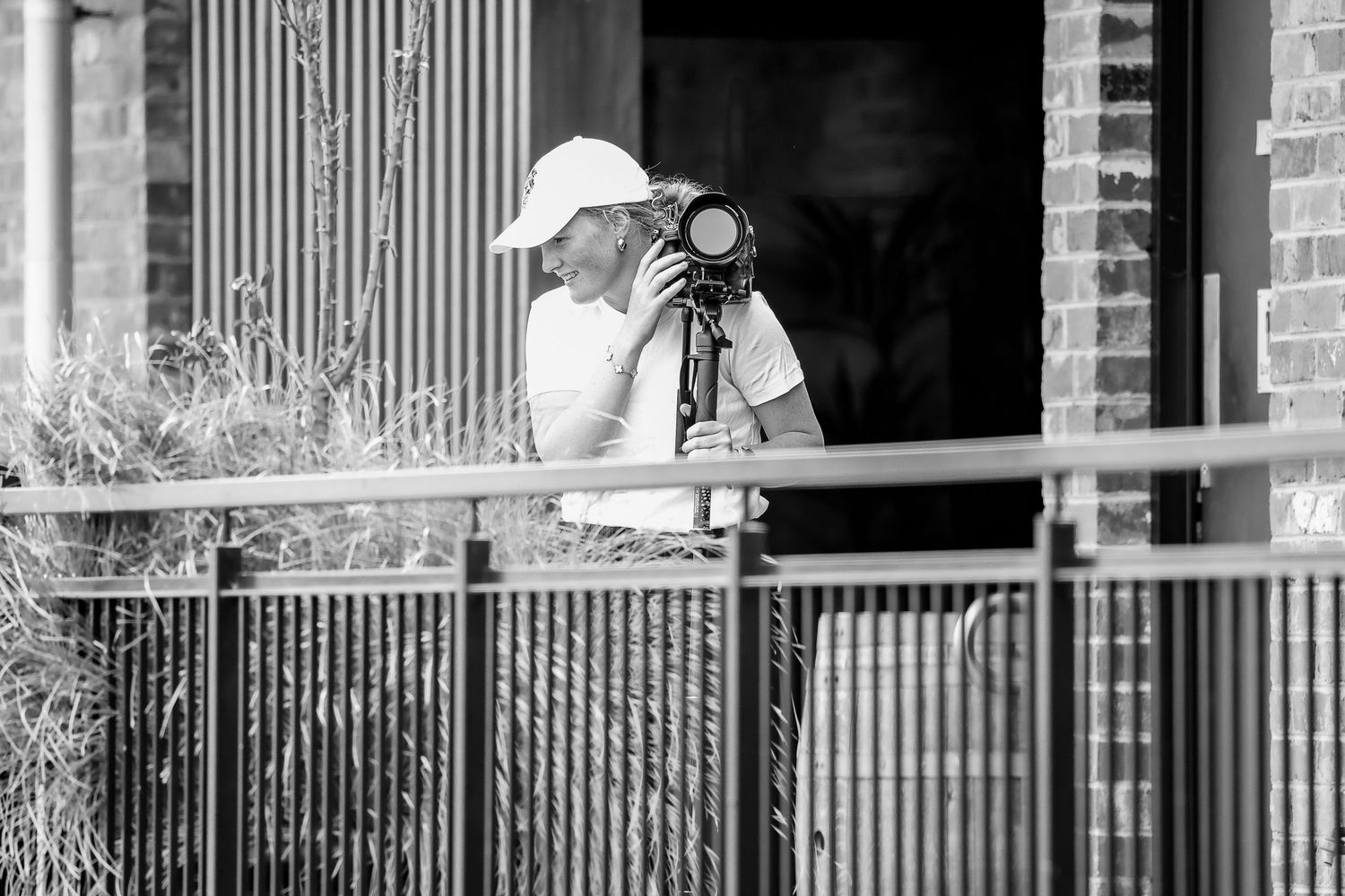 White metal railing with photographers setting up camera equipment in black and white.