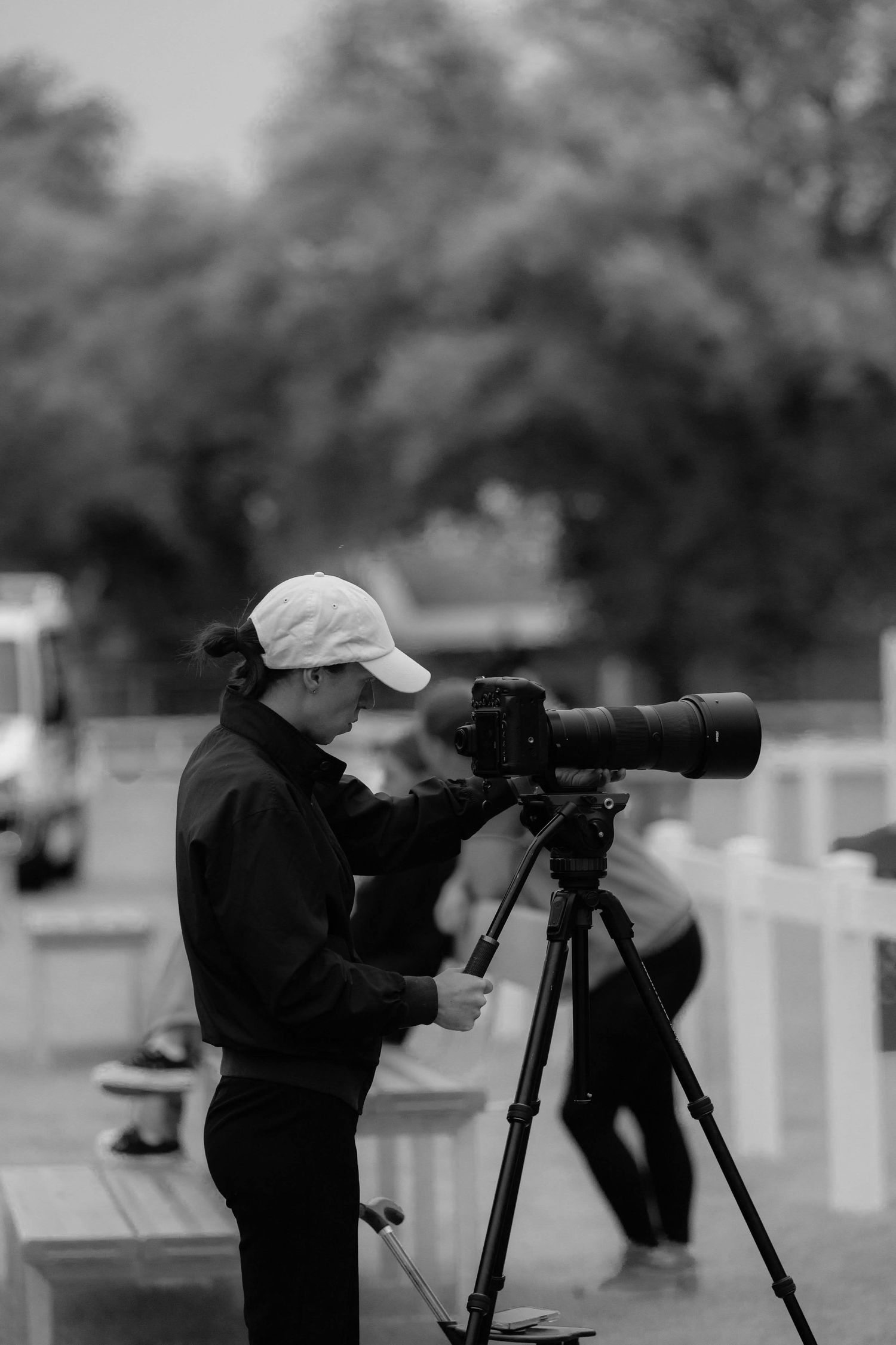 Line of photographers with cameras and tripods set up outdoors in monochrome.
