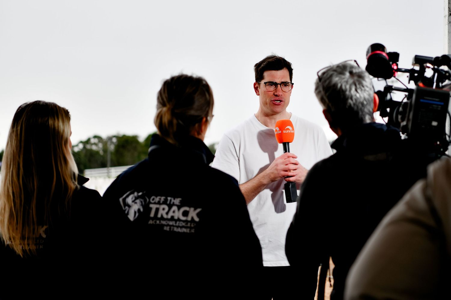 Media interview being conducted with camera crew and microphone outdoors.