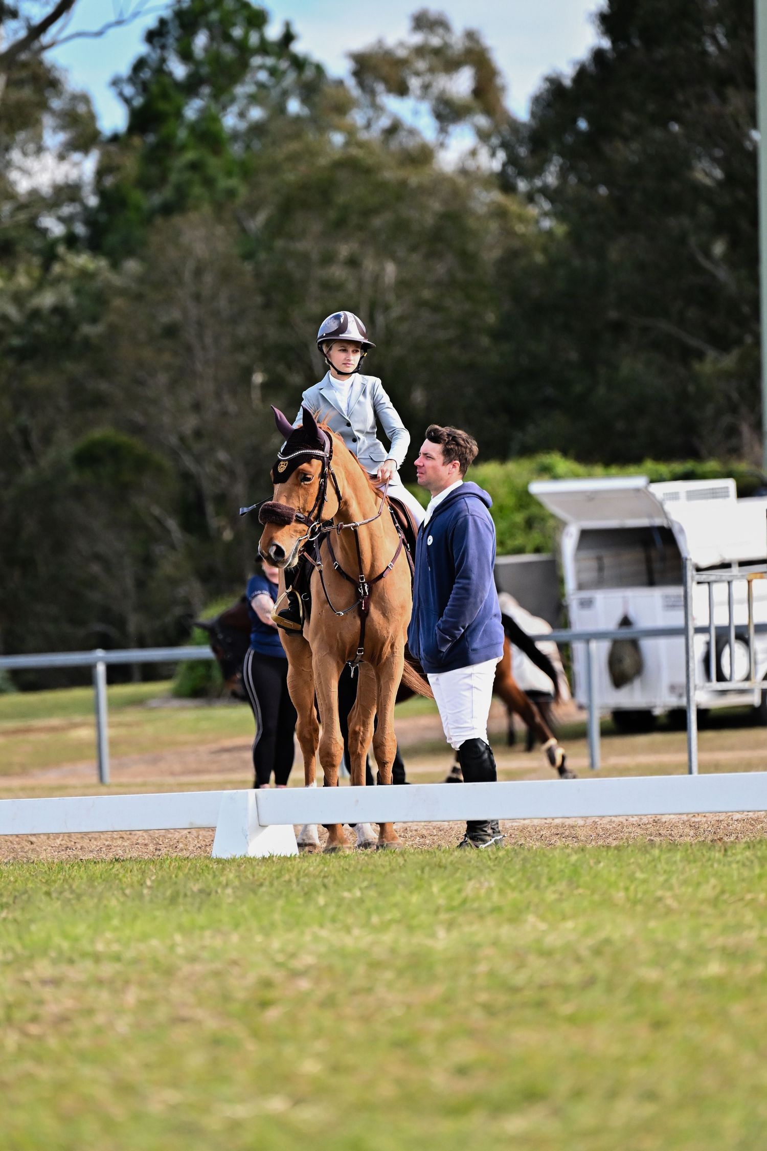 Horse and rider in competition setting with handler alongside.