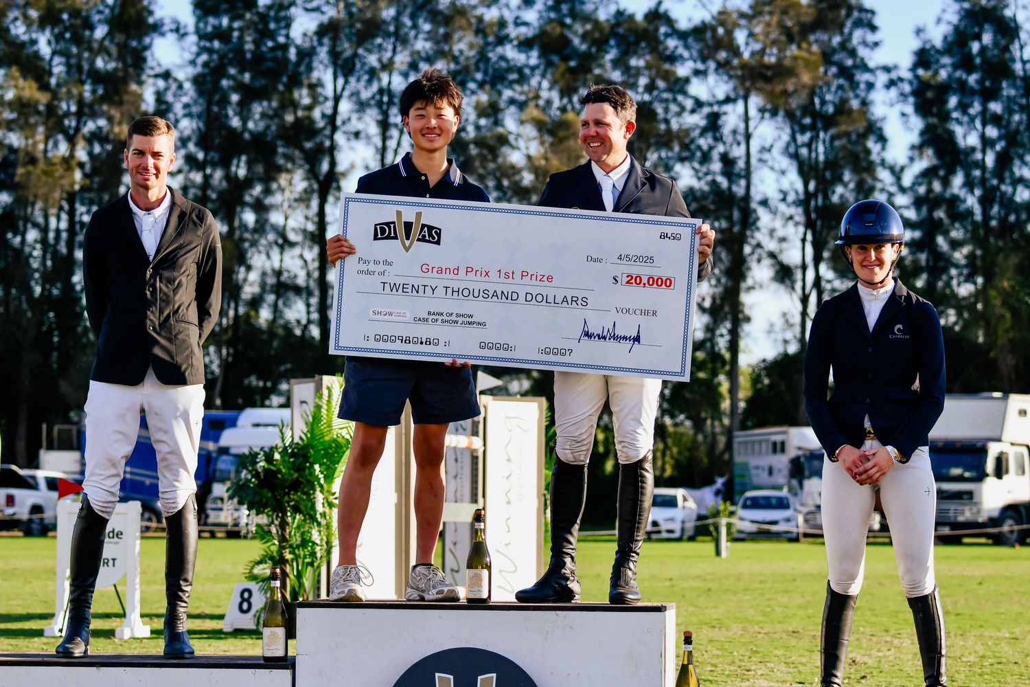Winners on podium holding large check during equestrian award ceremony.