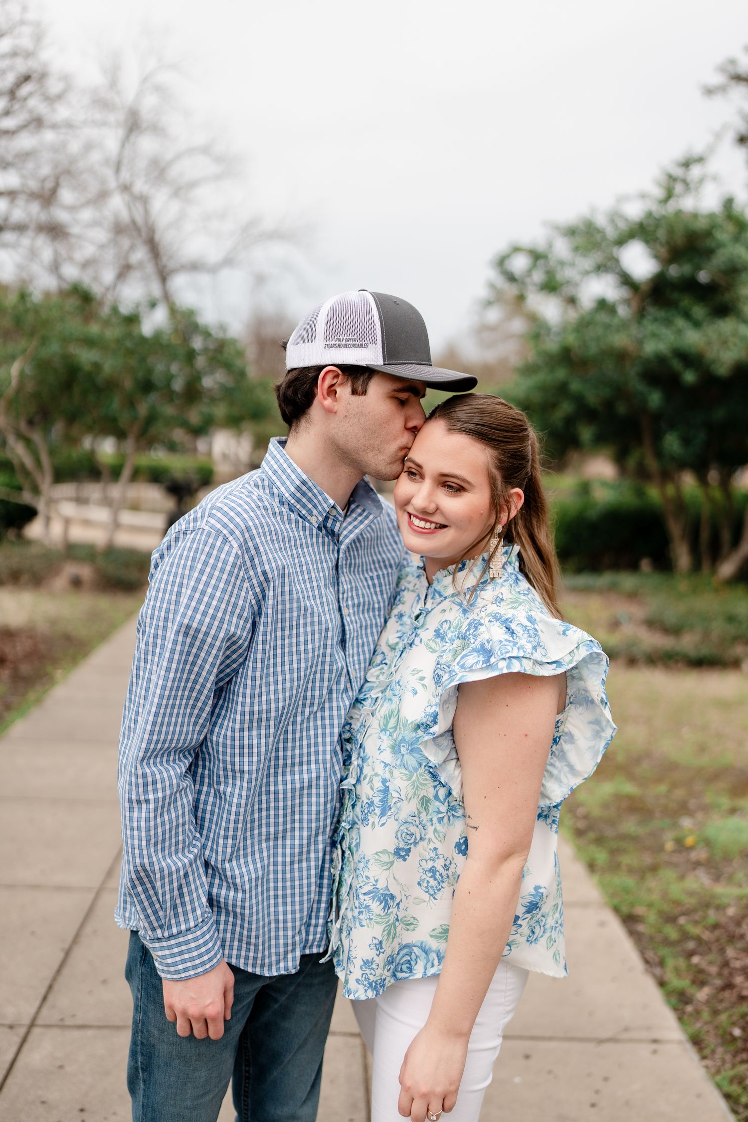 A couple shares an intimate moment while standing on a garden pathway.