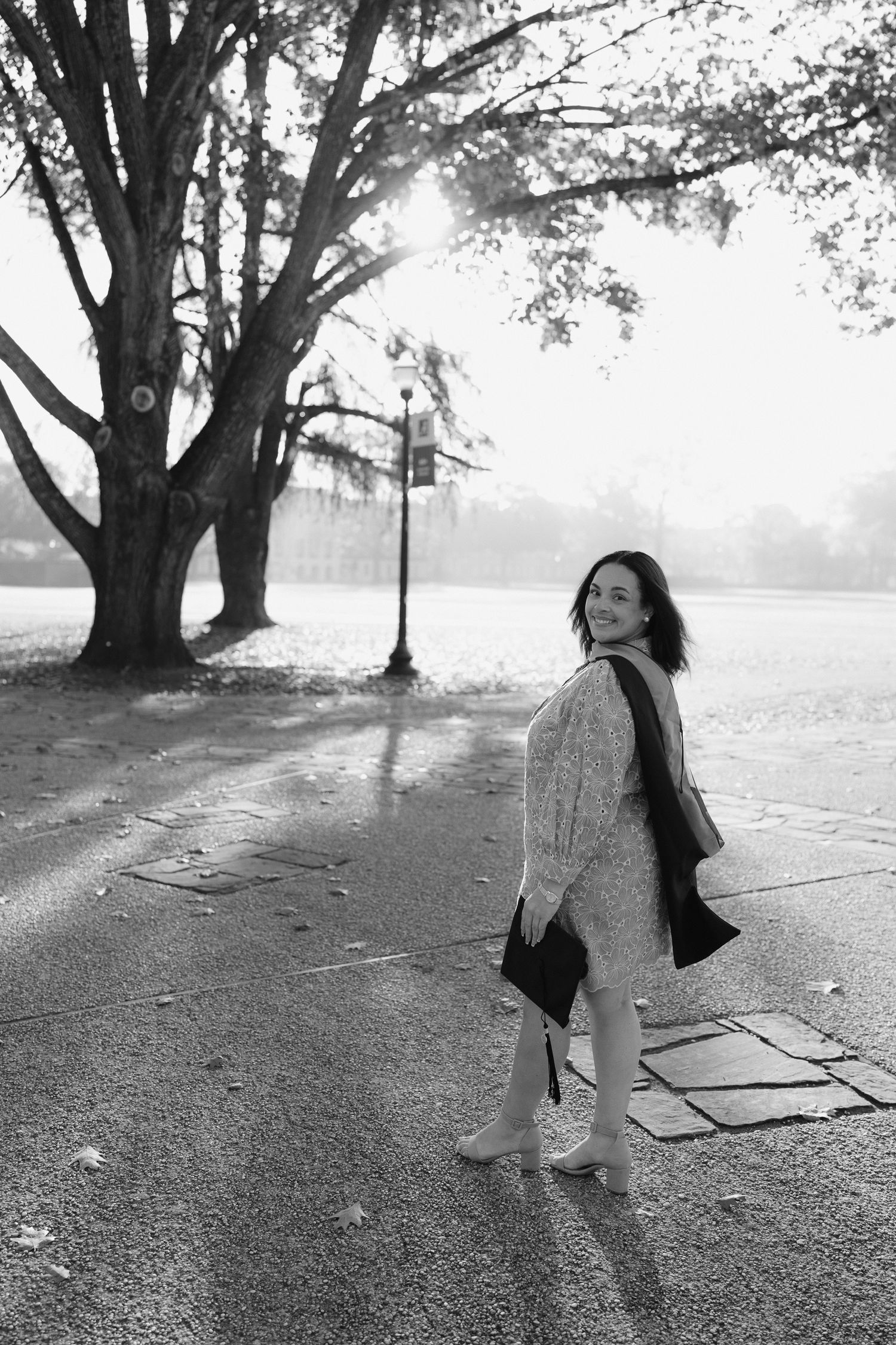 Black and white graduation portraits under large trees with dramatic lighting.