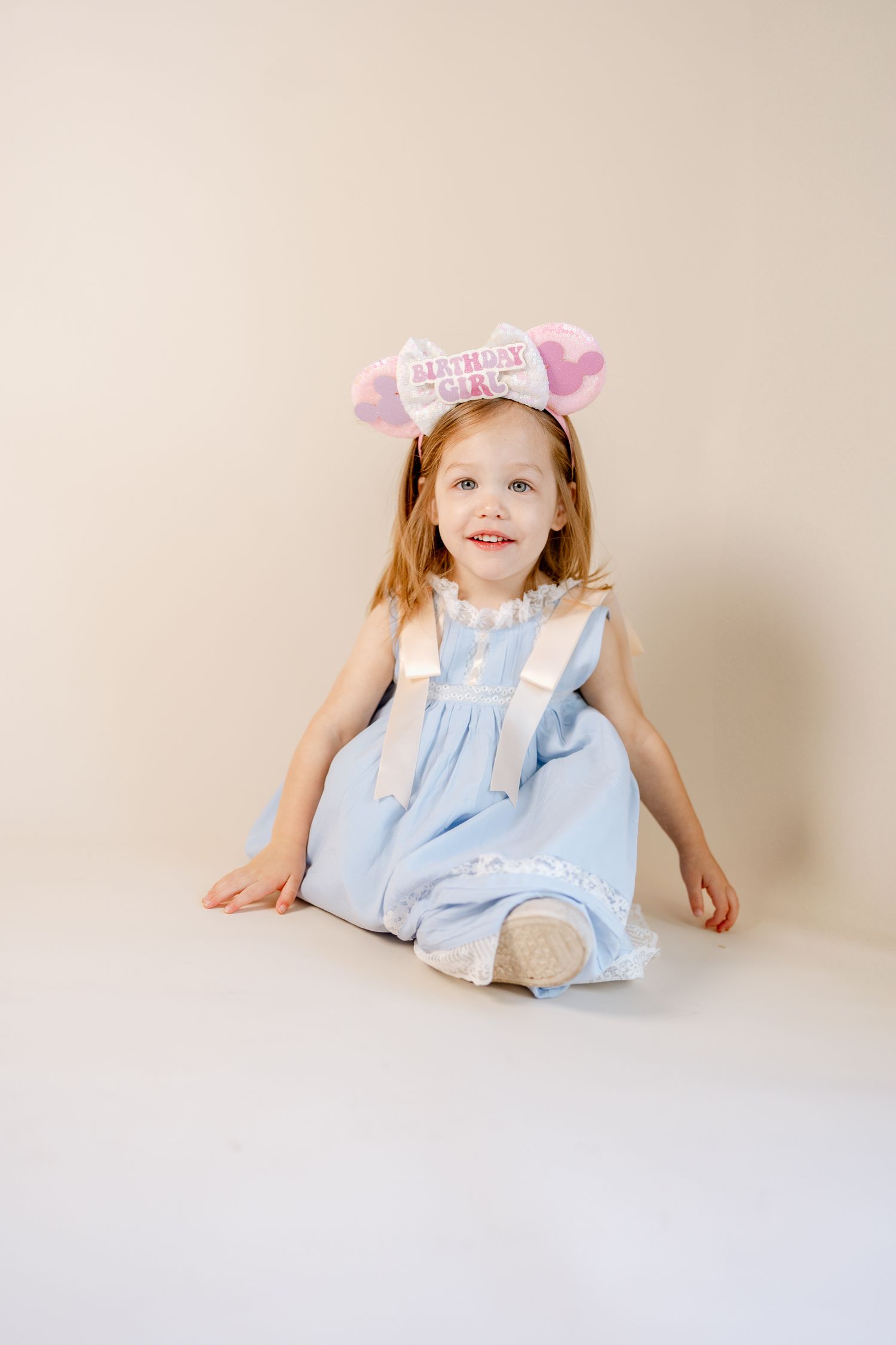Sweet portrait series with child in blue dress against neutral backdrop.