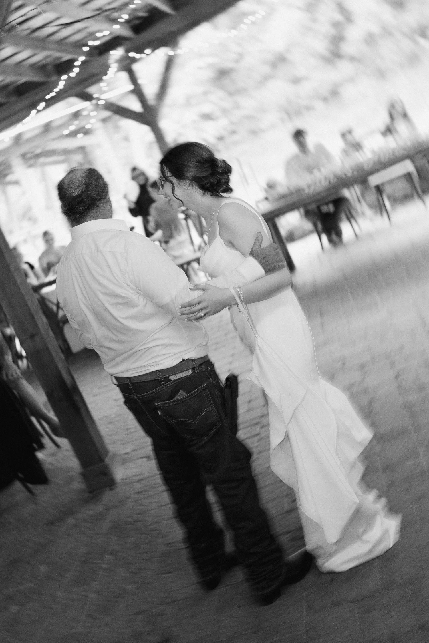 Blurred black and white photo of bride and groom sharing intimate first dance at wedding reception.