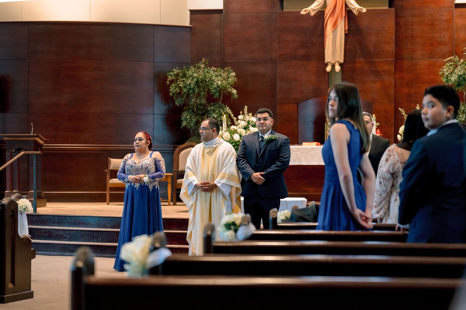 A church wedding ceremony shows bridesmaids in blue dresses and groomsmen in suits standing at the altar.