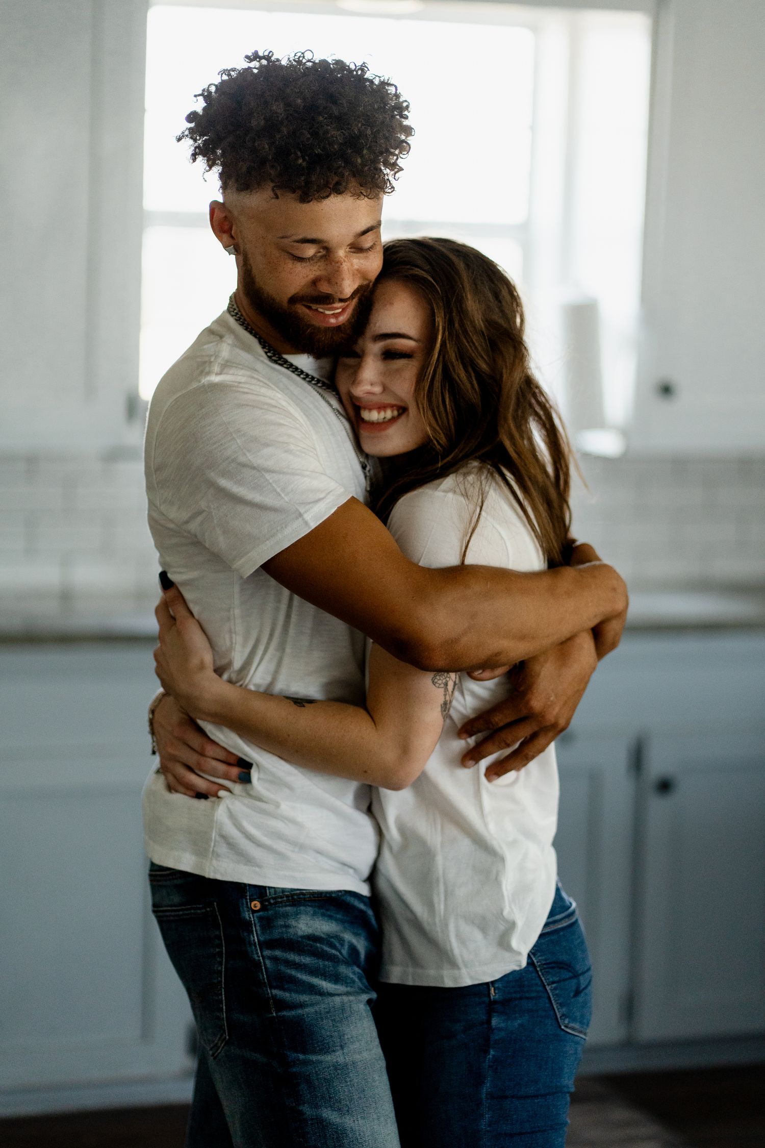 A joyful couple embraces and laughs together in a bright indoor setting.