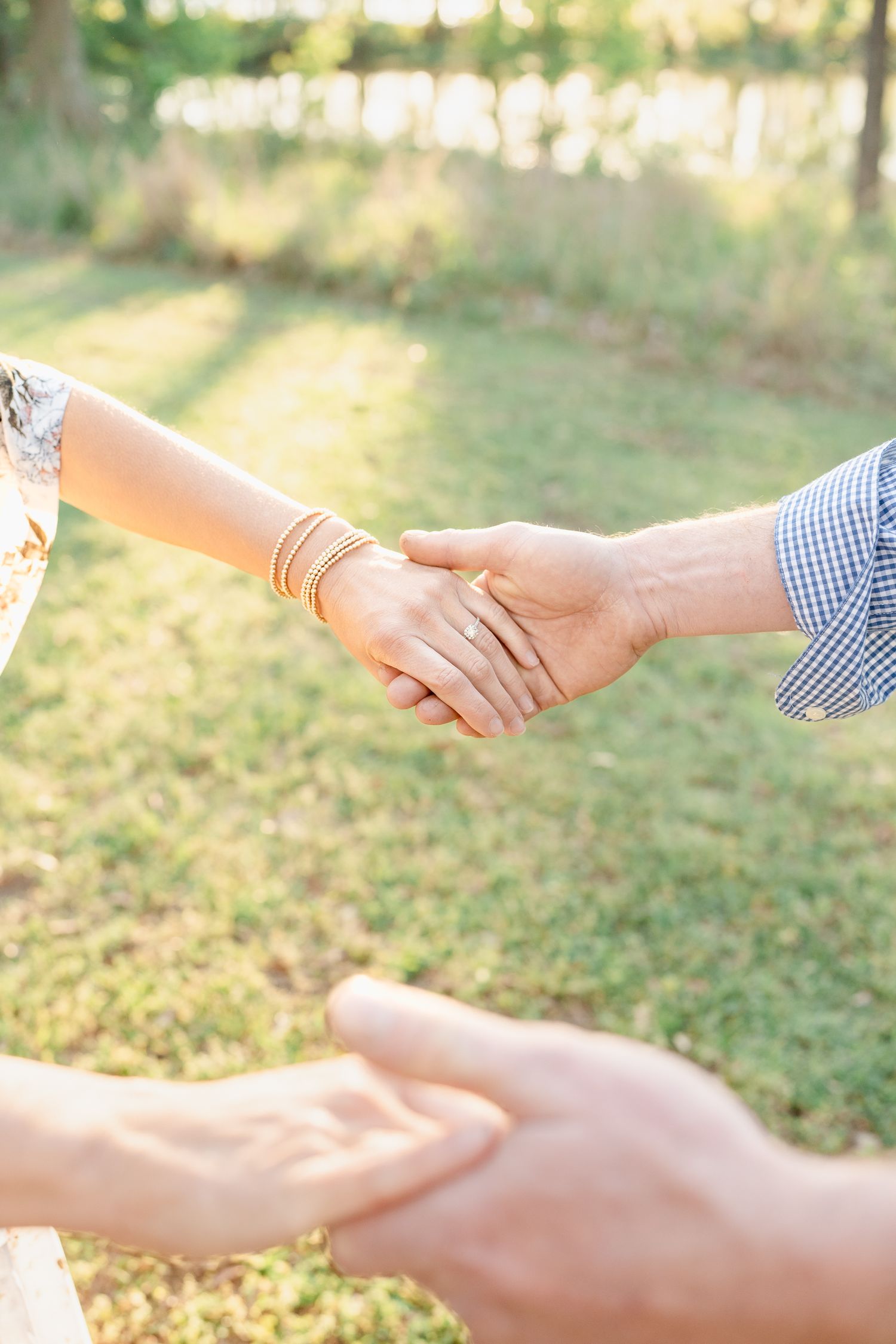 Close-up of hands joining together outdoors in golden sunlight.