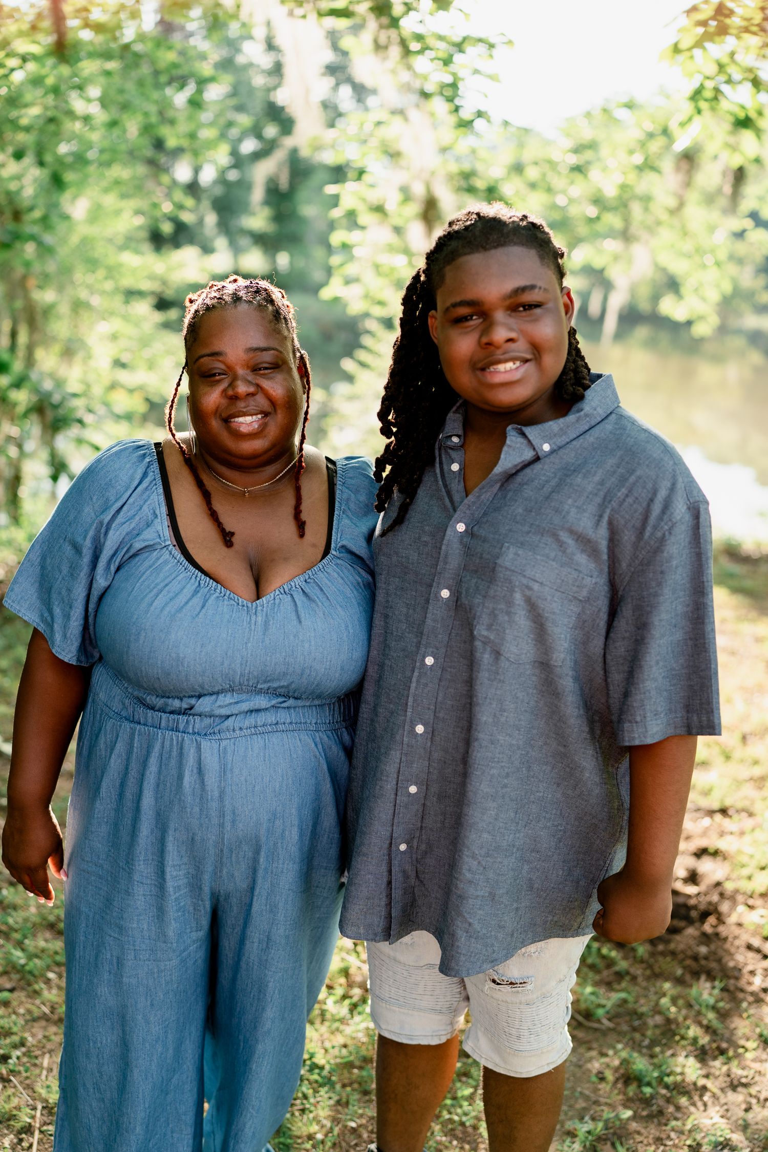 Family members in coordinated blue and gray outfits smile warmly during an outdoor portrait session.