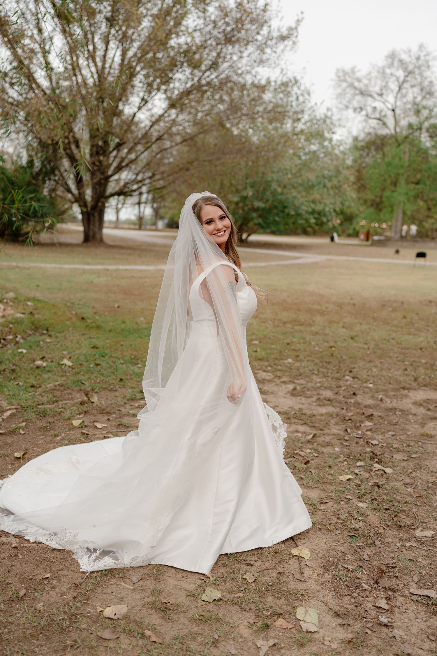 Elegant white wedding dress with flowing train captured in outdoor garden setting.