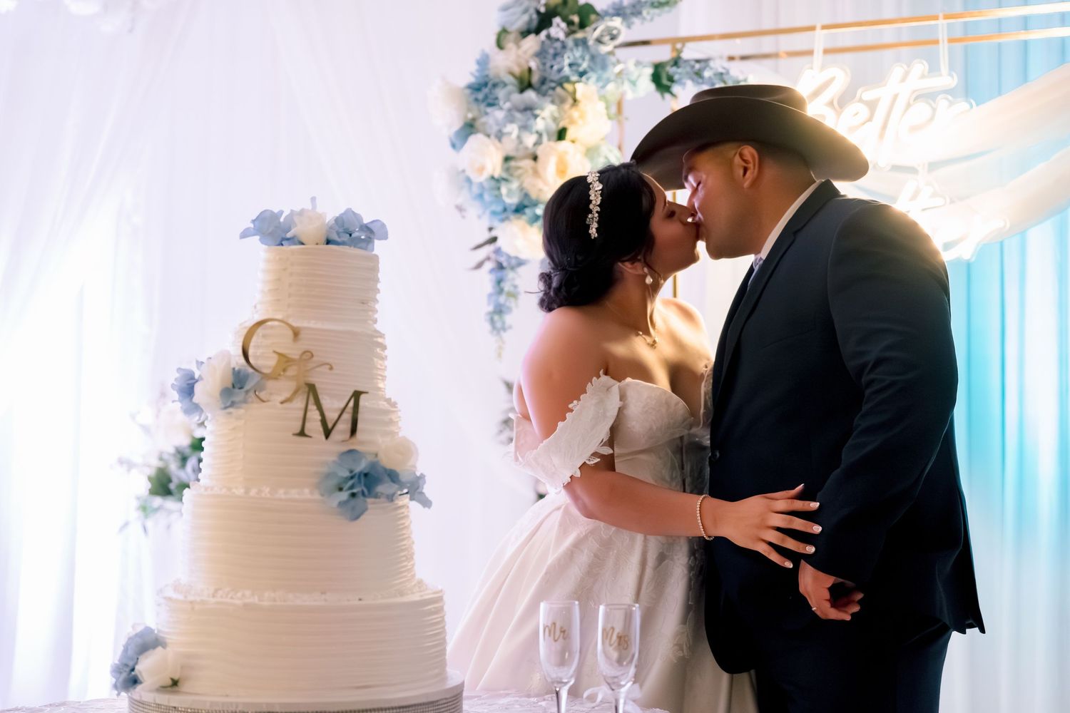Elegant white wedding cake with monogram and floral decorations at reception.