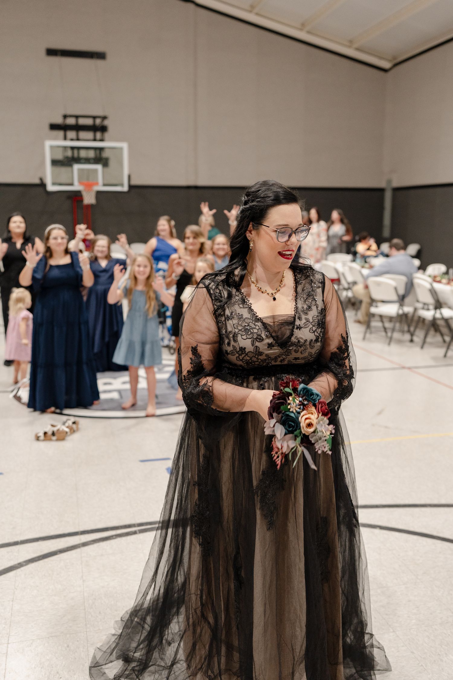 A flowing black tulle dress with lace details is displayed in a church gymnasium setting.
