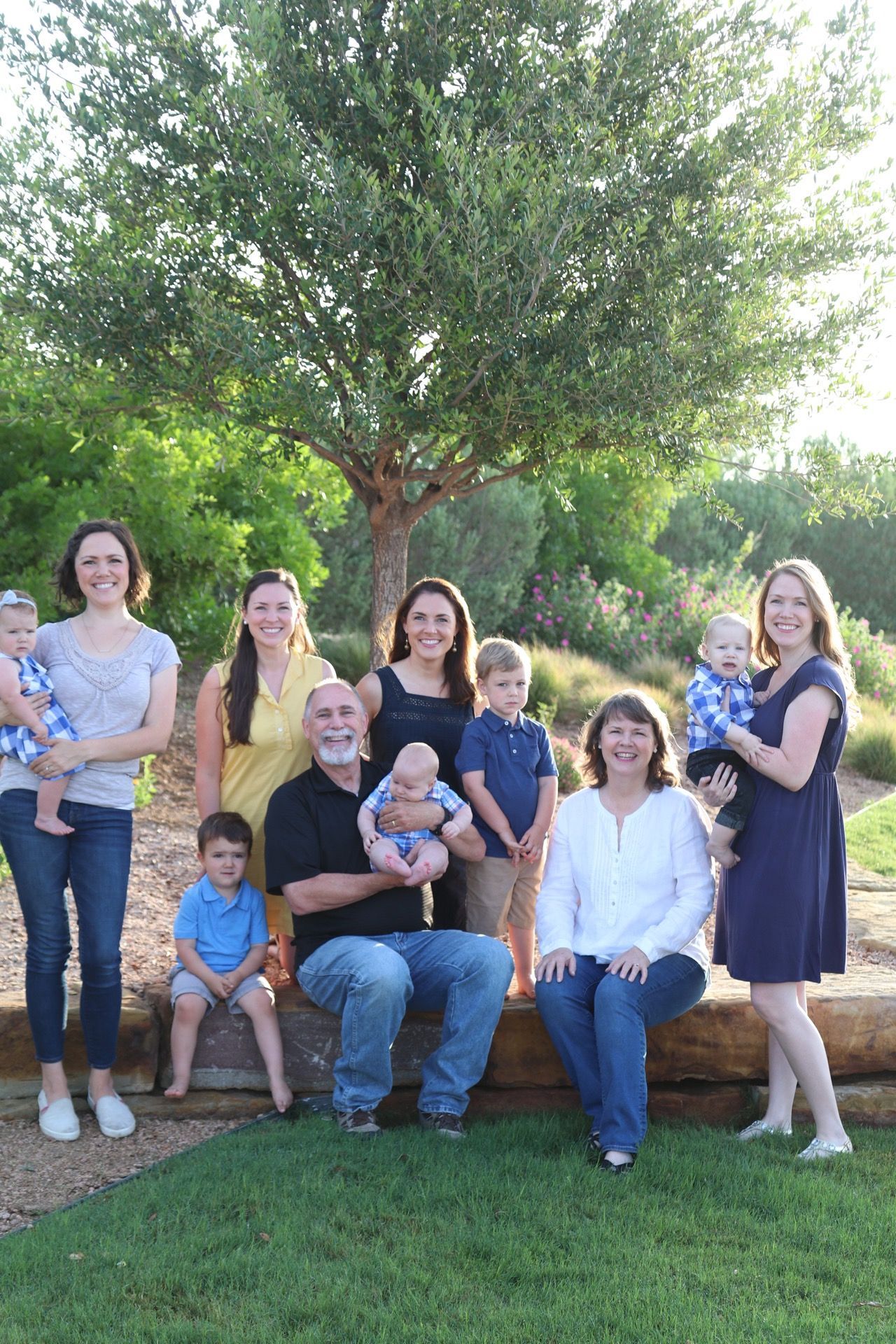 Large family group sitting together on a fallen log outdoors for a casual portrait.