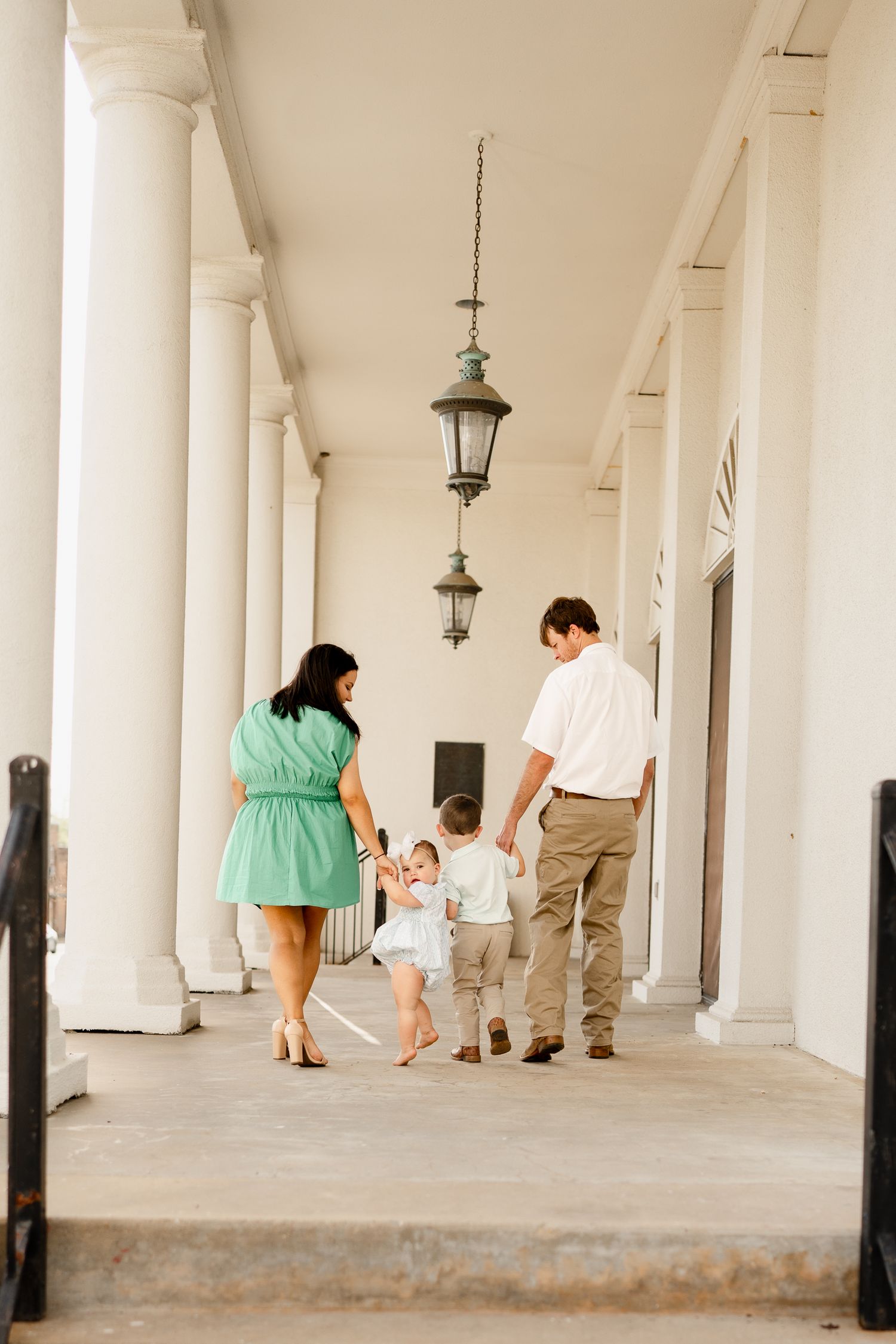 Family walking together down a columned hallway with small children holding hands.