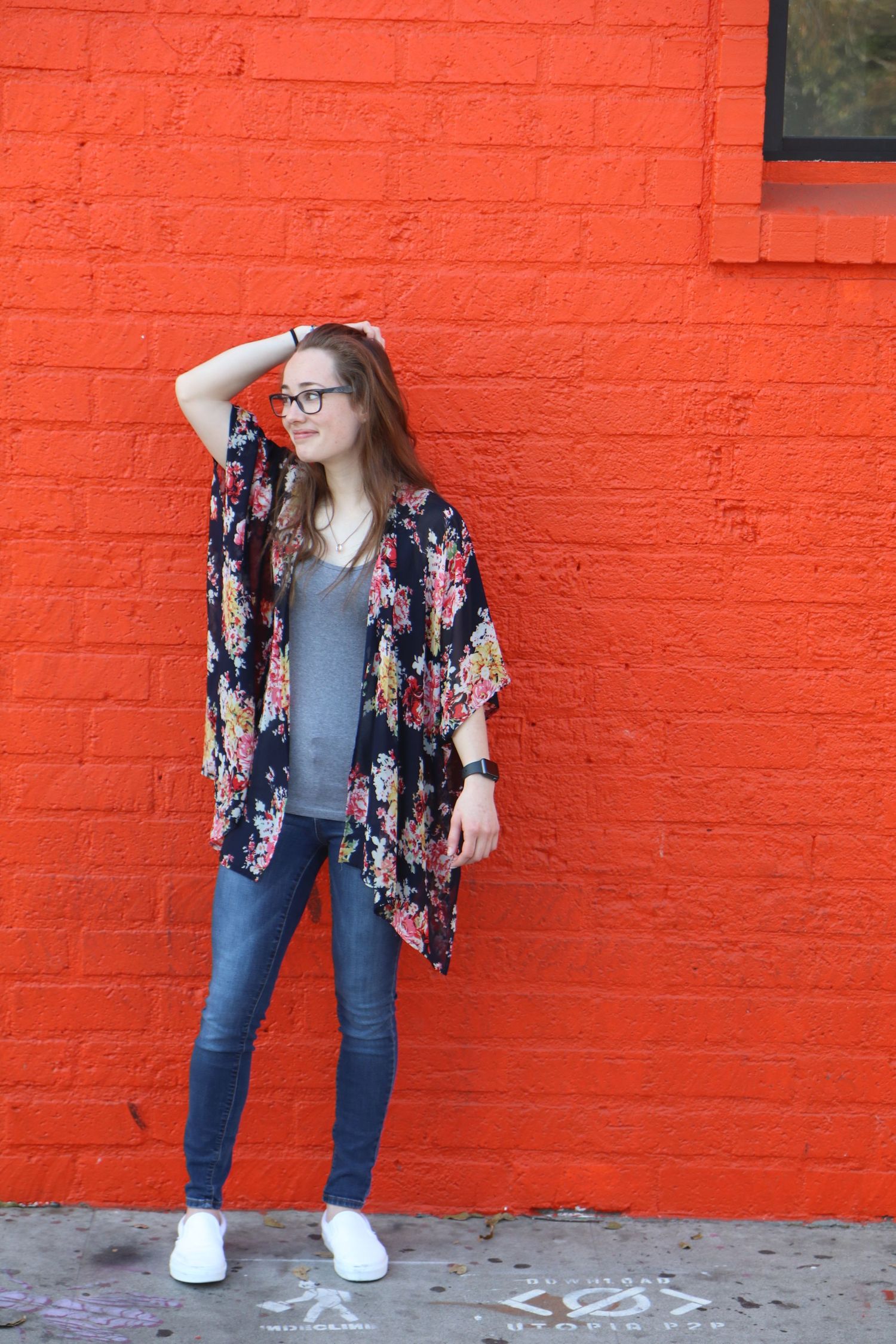 Fashion photography against a bright red brick wall showcasing a floral kimono and casual attire.