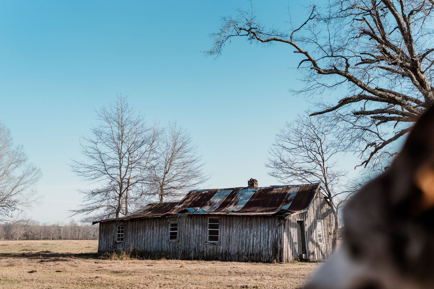 Old weathered barn with solar panels on roof against bright blue sky.