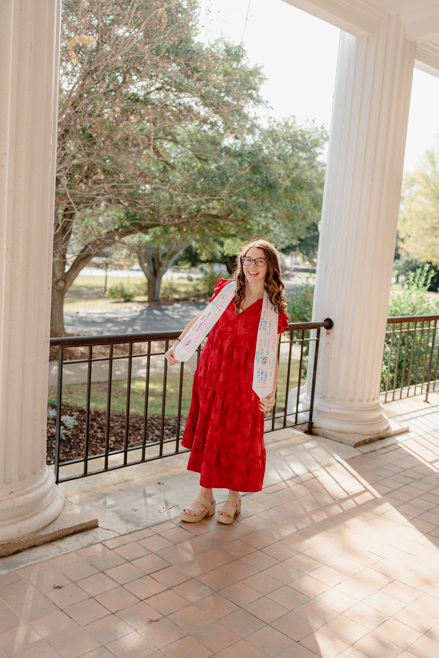A series of photos showing someone in a bright red dress twirling on a columned porch with natural lighting.
