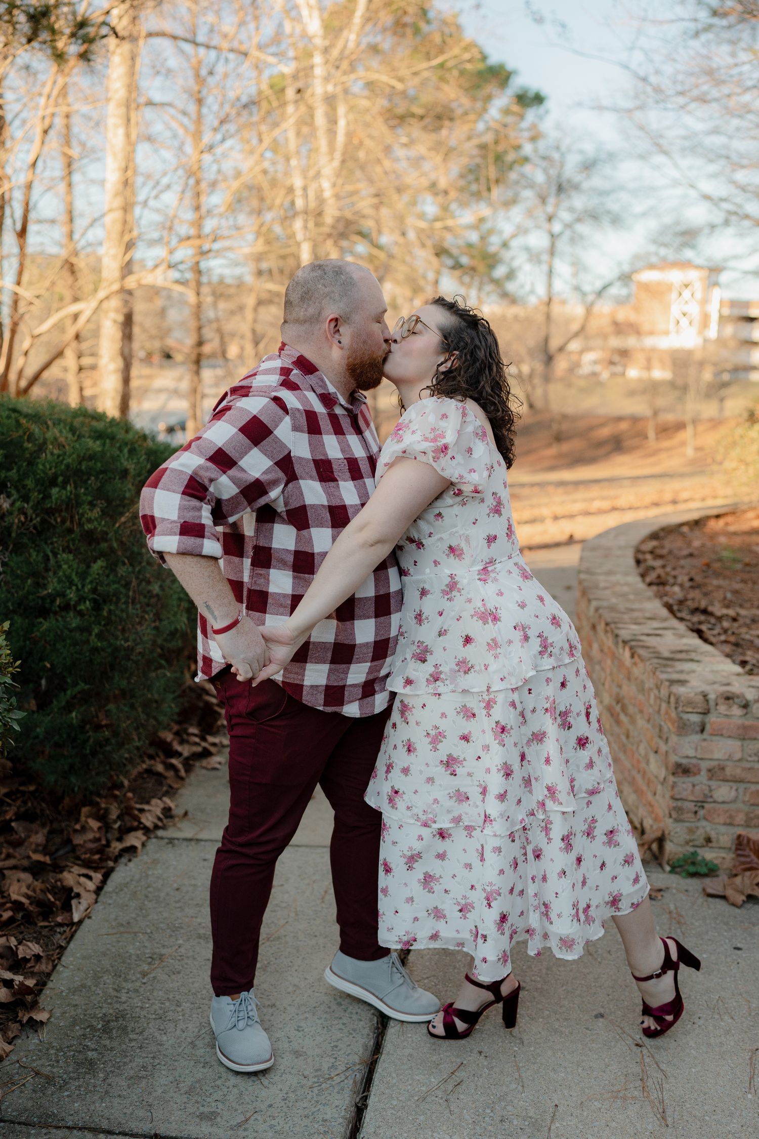 Couple in coordinating red and white outfits share an intimate moment on a park pathway.