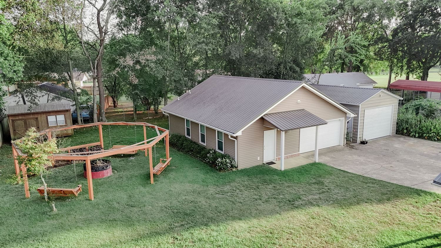 A large backyard with green grass, trees, and wooden fencing structures visible from multiple angles.