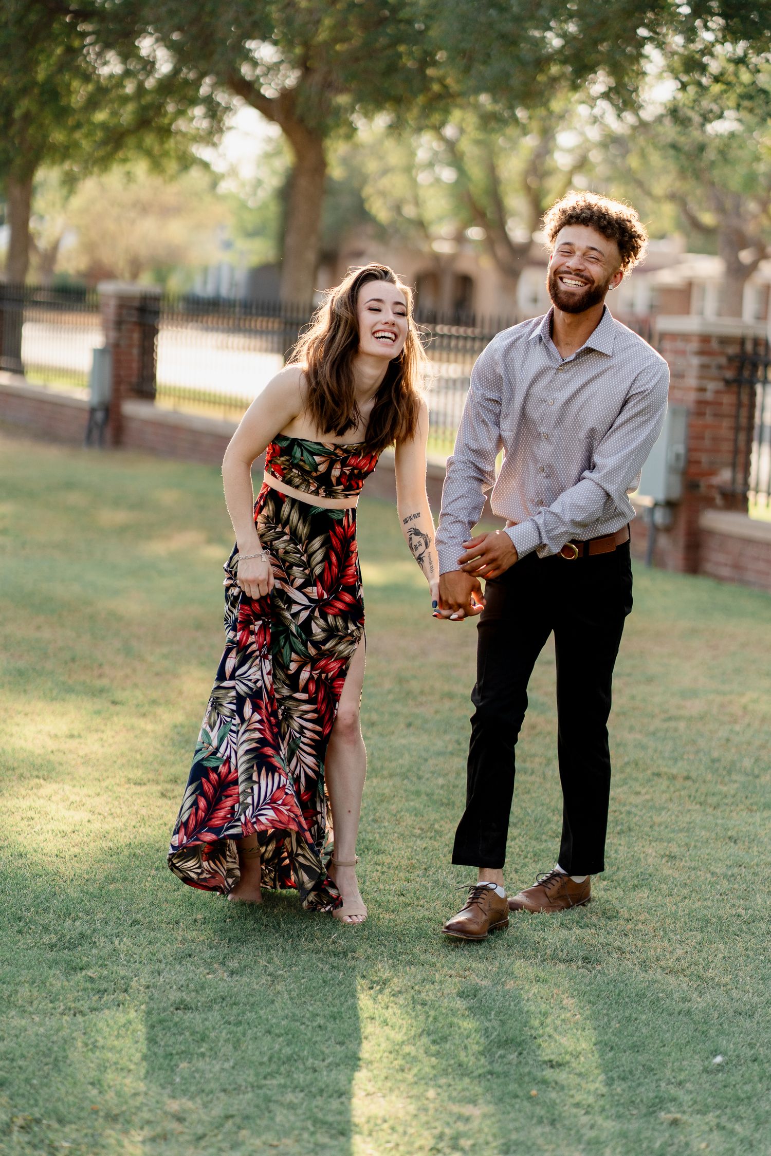 A playful couple poses together on a sunny lawn during their outdoor photoshoot.