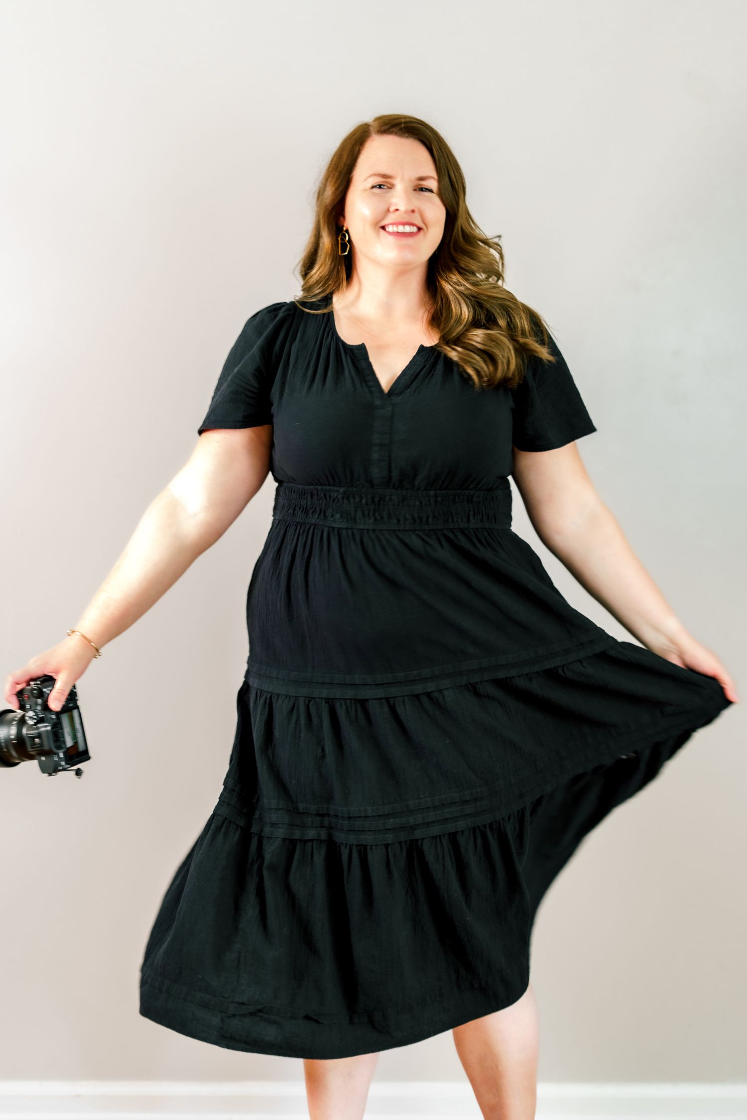 Multiple poses in a flowing black dress showing movement and joy against a white backdrop.