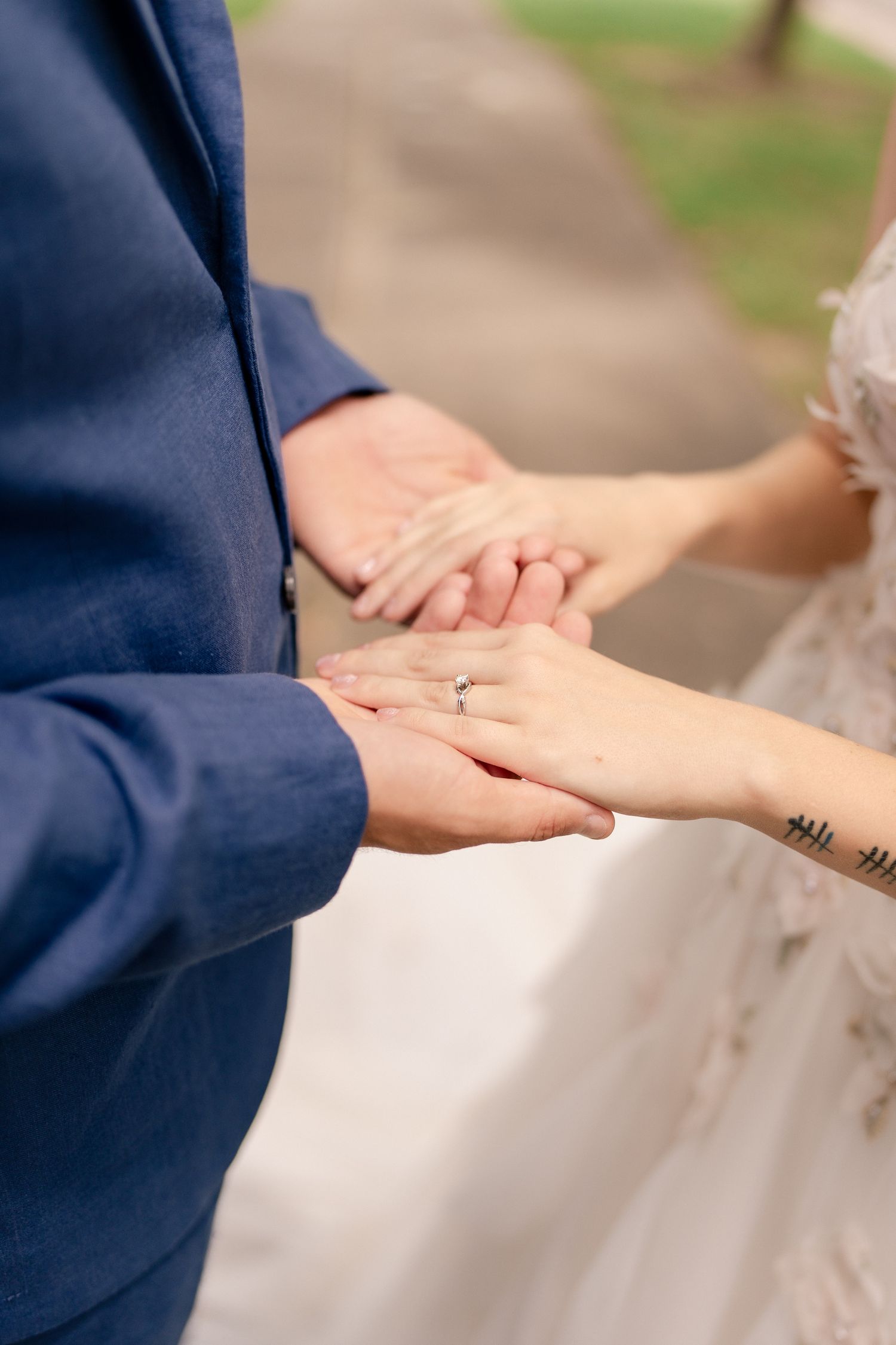 Close-up shots of hands touching and holding during an outdoor wedding ceremony.