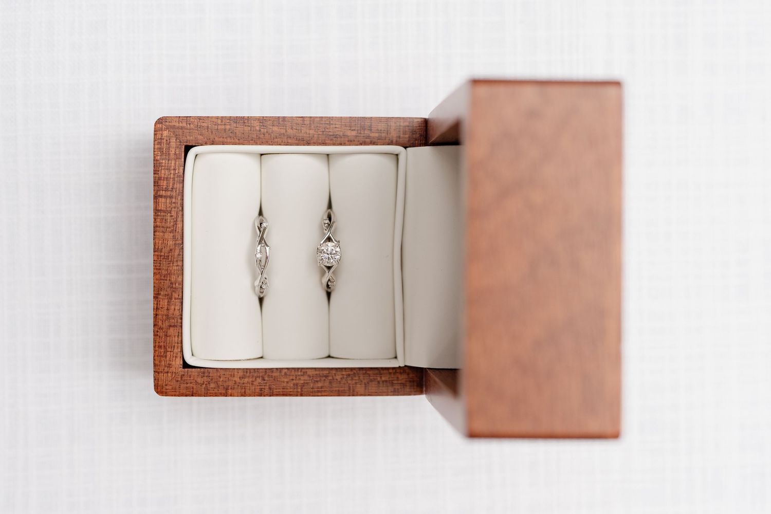Wooden ring box with white cushioned interior sliding open to reveal storage space.