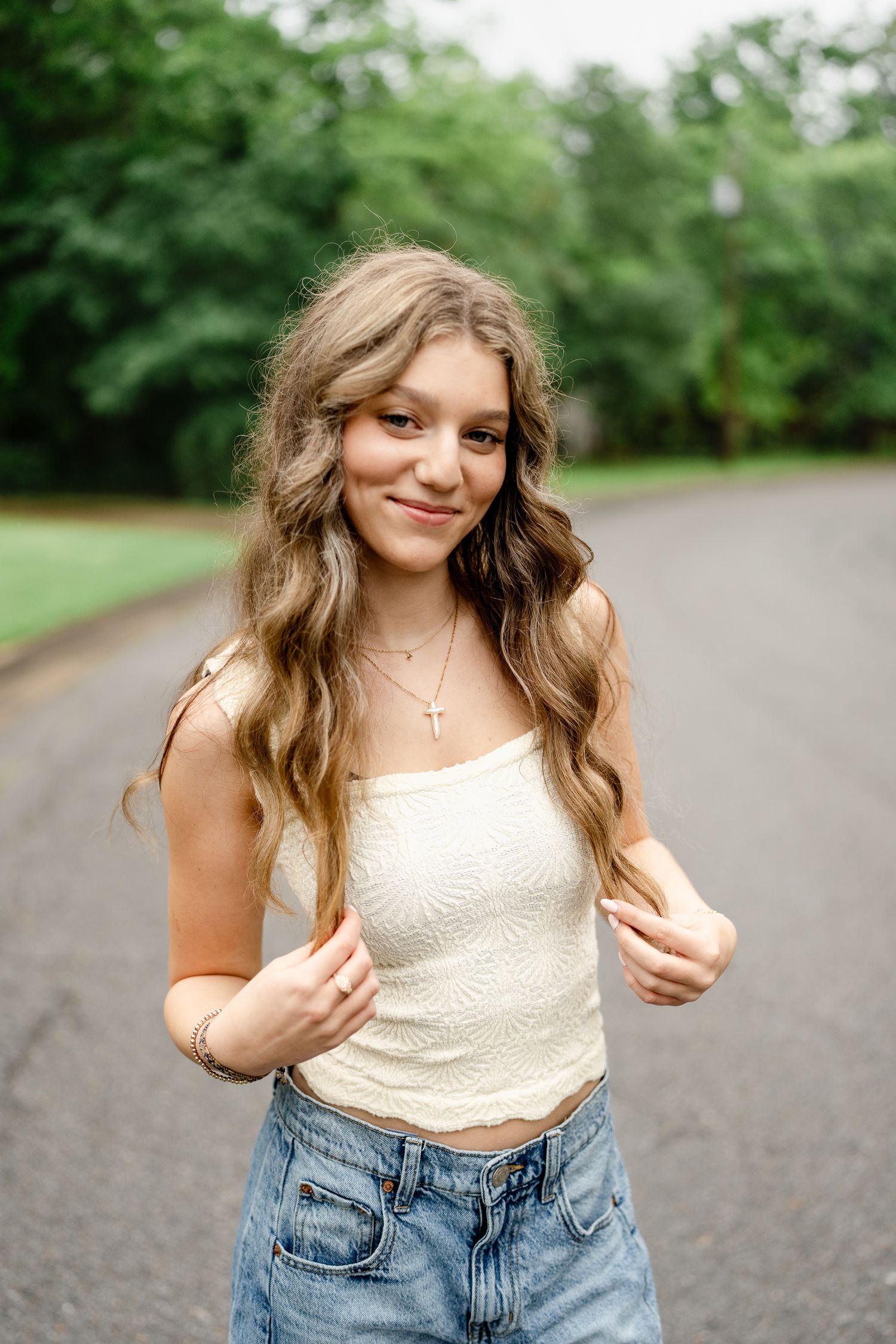 Casual summer outfit with white top and denim jeans captured on an outdoor path.