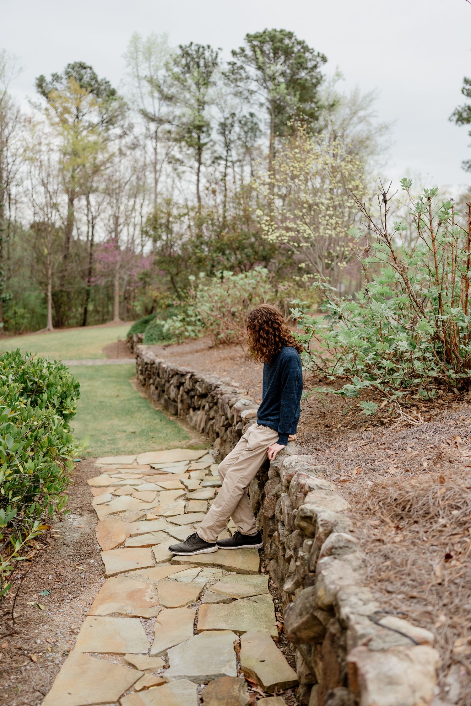 Flagstone walkway bordered by rugged stone wall in peaceful outdoor setting.